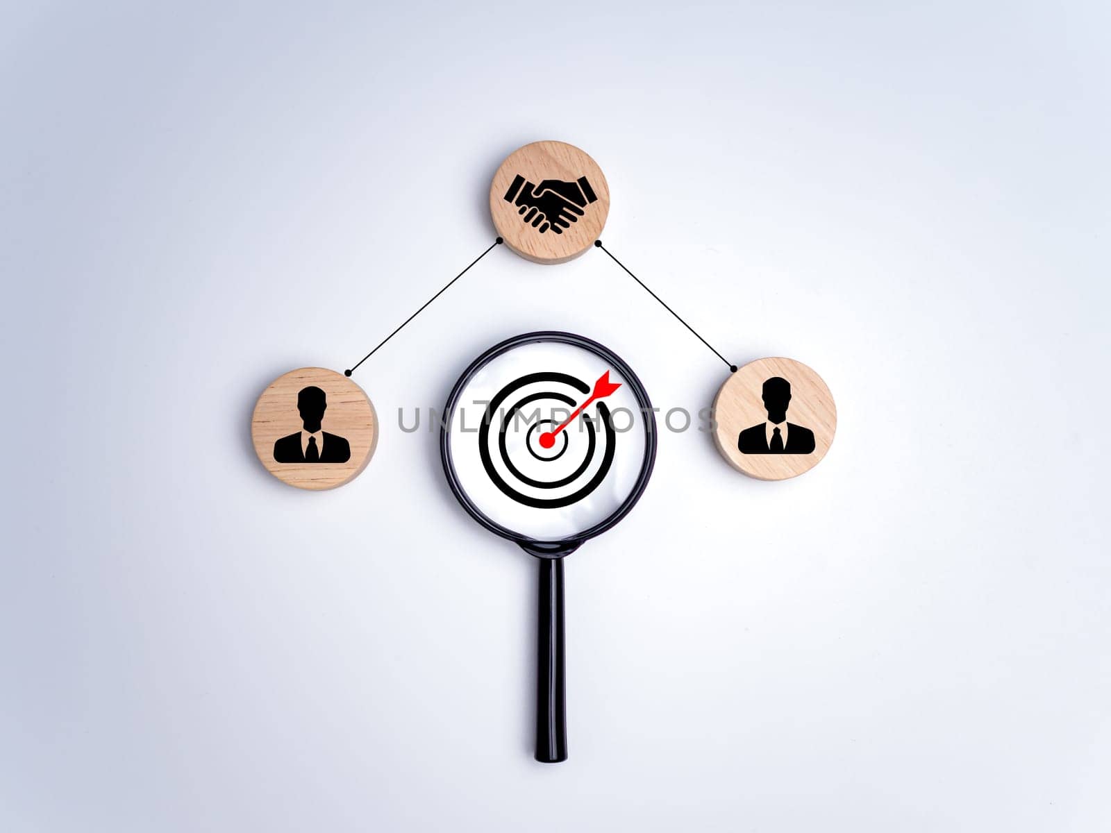 Magnifying glass with dart board and circular pieces of wood printed with human symbols, cooperation, teamwork, training, Collaboration and cooperation, Social connections, joining to solve tasks.