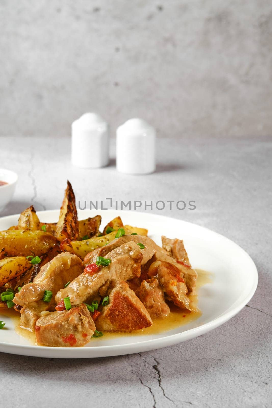 Closeup view of plate with beef goulash with baked in oven potato wedges