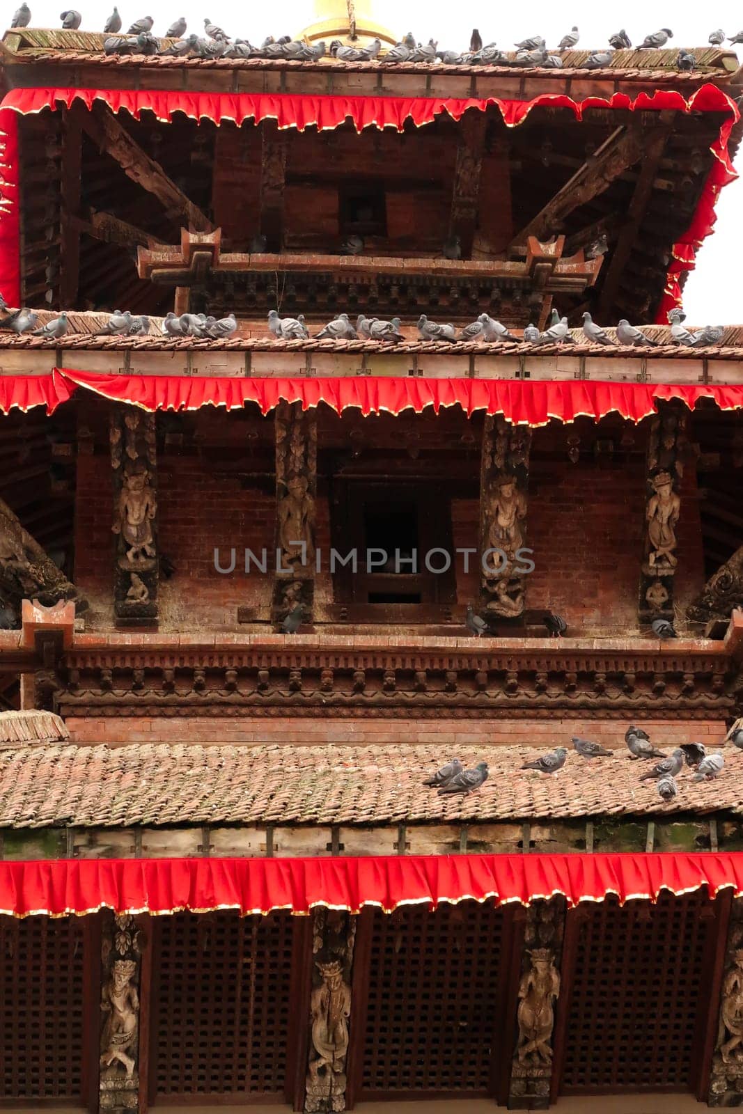 Closer look on the architecture of one of the temples of Durbar Square, many pigeons are sitting on its roofs, Kathmandu, Nepal 2022