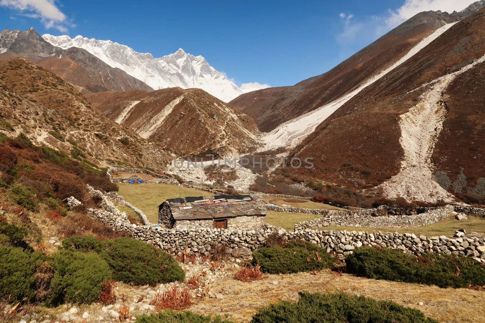 A traditional stone farmhouse with slate roof between Pangboche and Dingboche surrounded by stone walls, Mount Nuptse and Lhotse can be seen in the background, Mount Everest Base Camp Trek, EBC, Nepal 2022