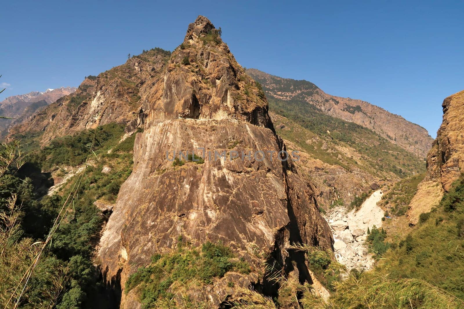View from the trail onto a giant rock, boulder, that has a part of the road from Besisahar, Bhulbhule to Chame, Manang carved into it, close to Tal village, Annapurna Circuit Trek, Nepal 2022
