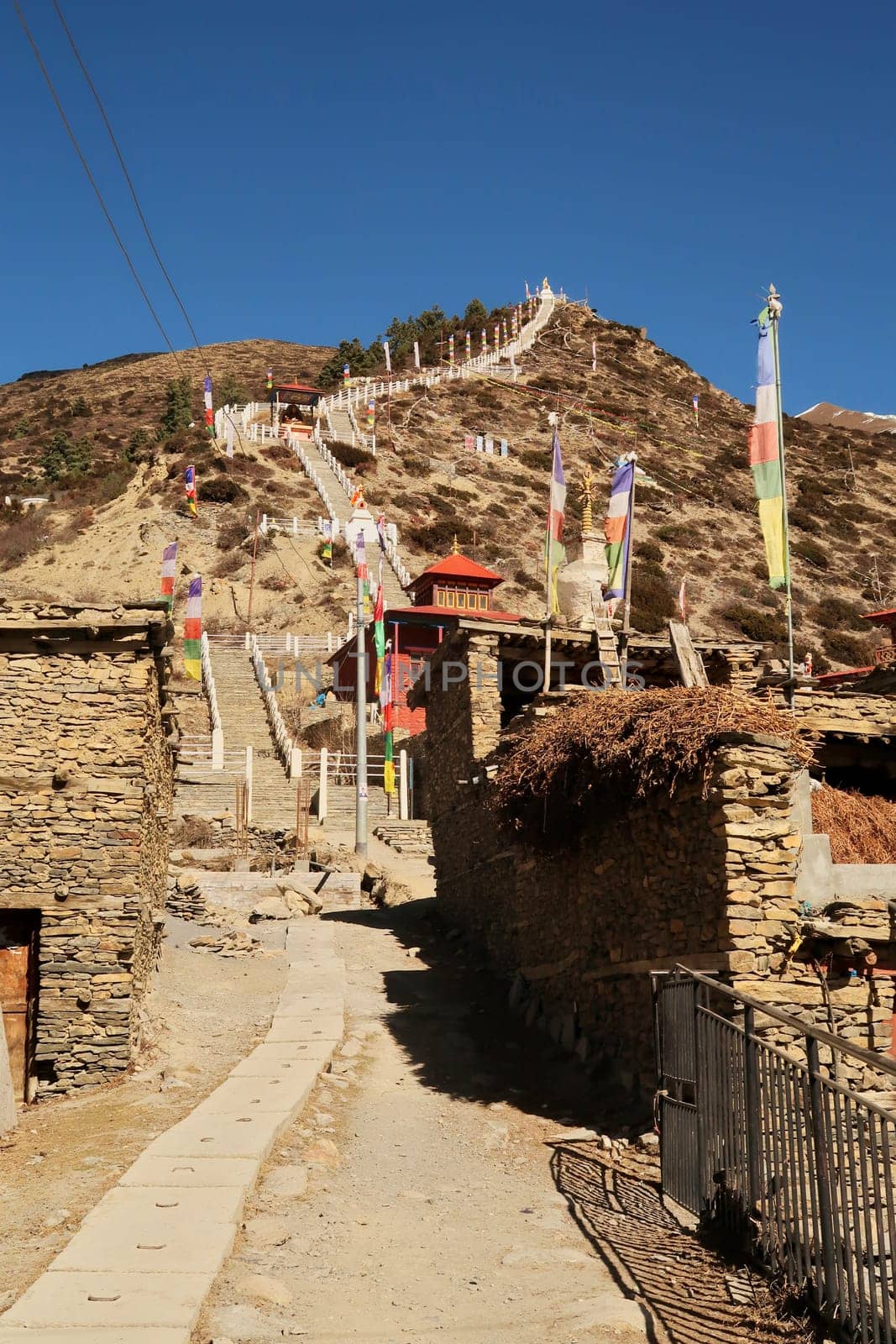 Many stairs are leading up to the Guru Rinpoche Statue and a stupa, pagoda in the traditional mountain village of Ngawal, Annapurna Circuiti Trek, Nepal 2022