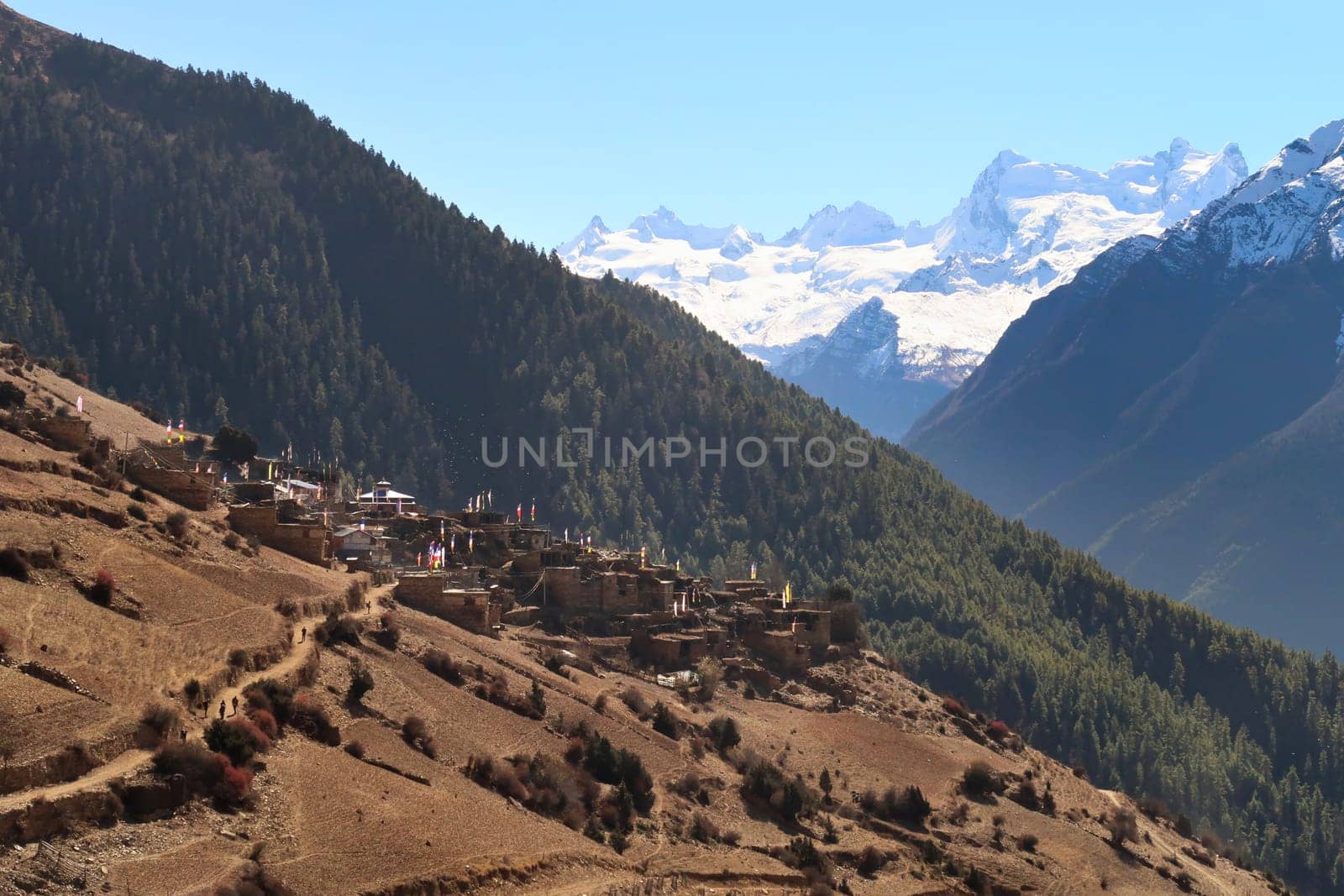 View from the trail to Manang back to the village of Ghyaru in front of the snow capped peak of Mount Lamjung Kailas, Himal, Annapurna Circuit Trek, Nepal 2022
