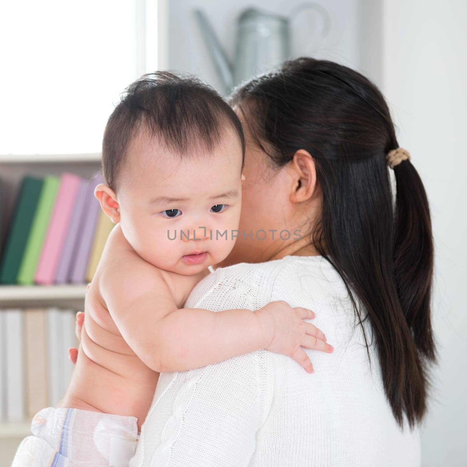 Asian mother pampering six months old baby girl at home.