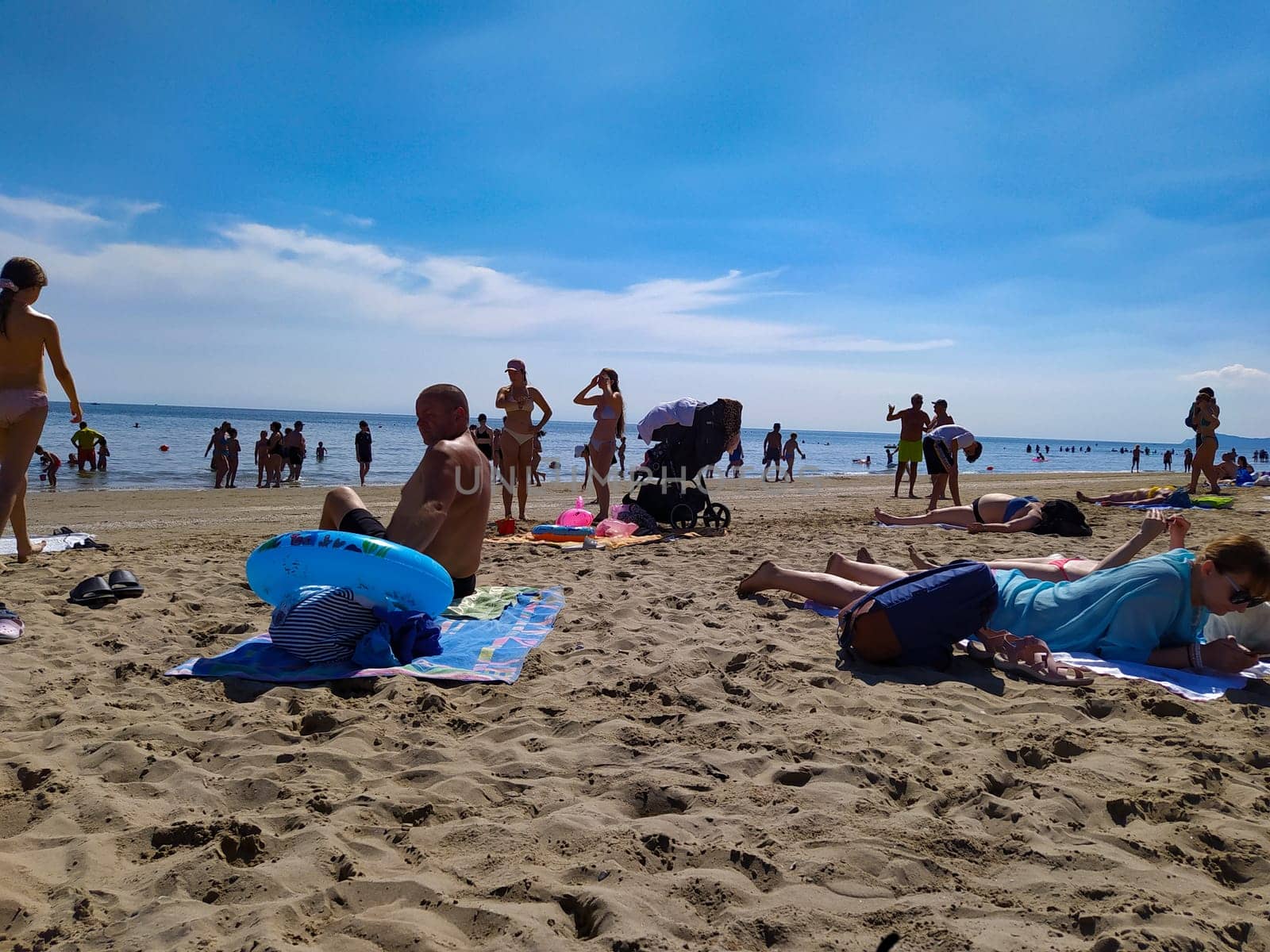 Rimini, Italy - June 25, 2024: People going along Rimini beach. The sunbeds and parasols on the beach