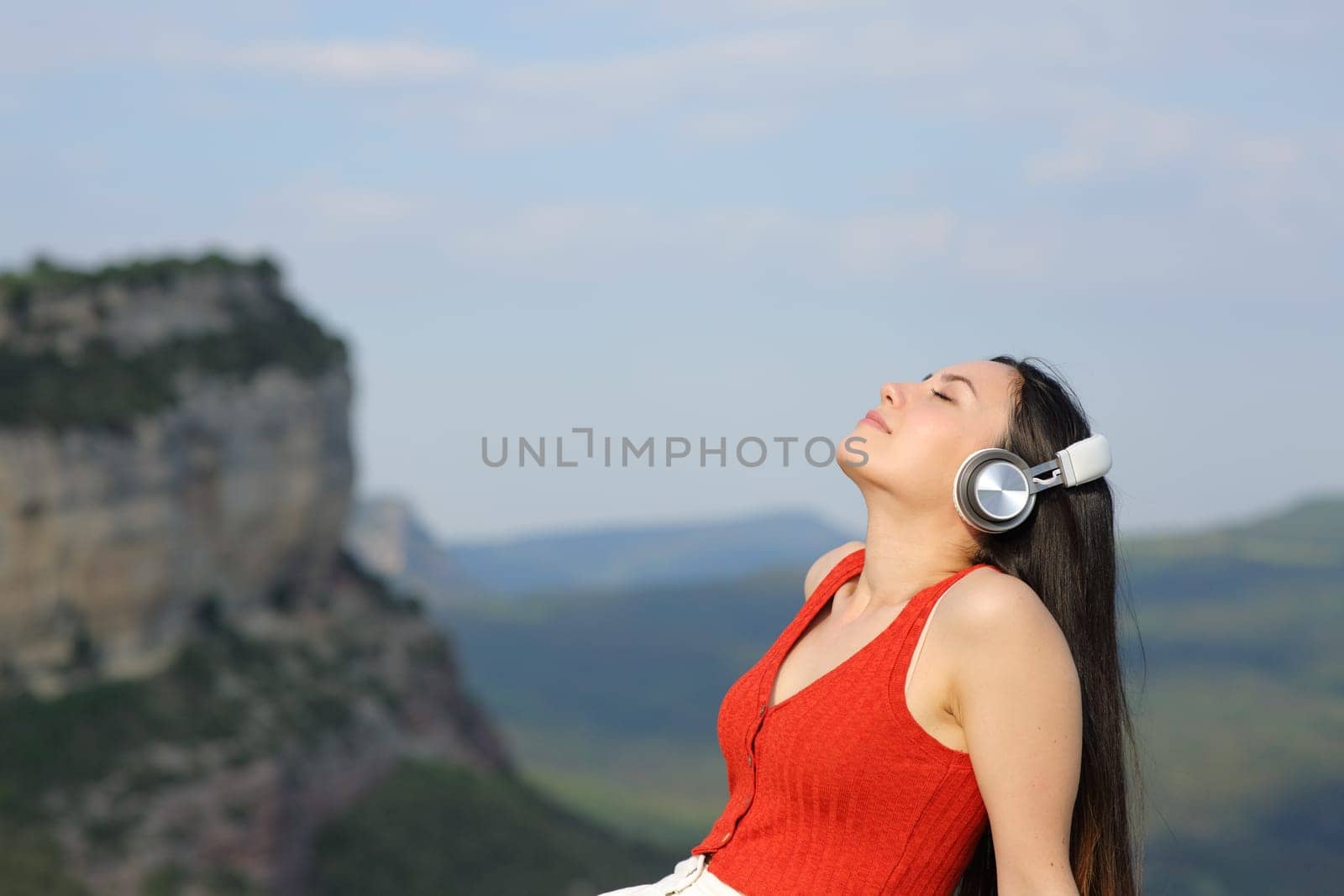 Asian woman wearing headphone relaxing and breathing fresh air listening audio sitting in nature