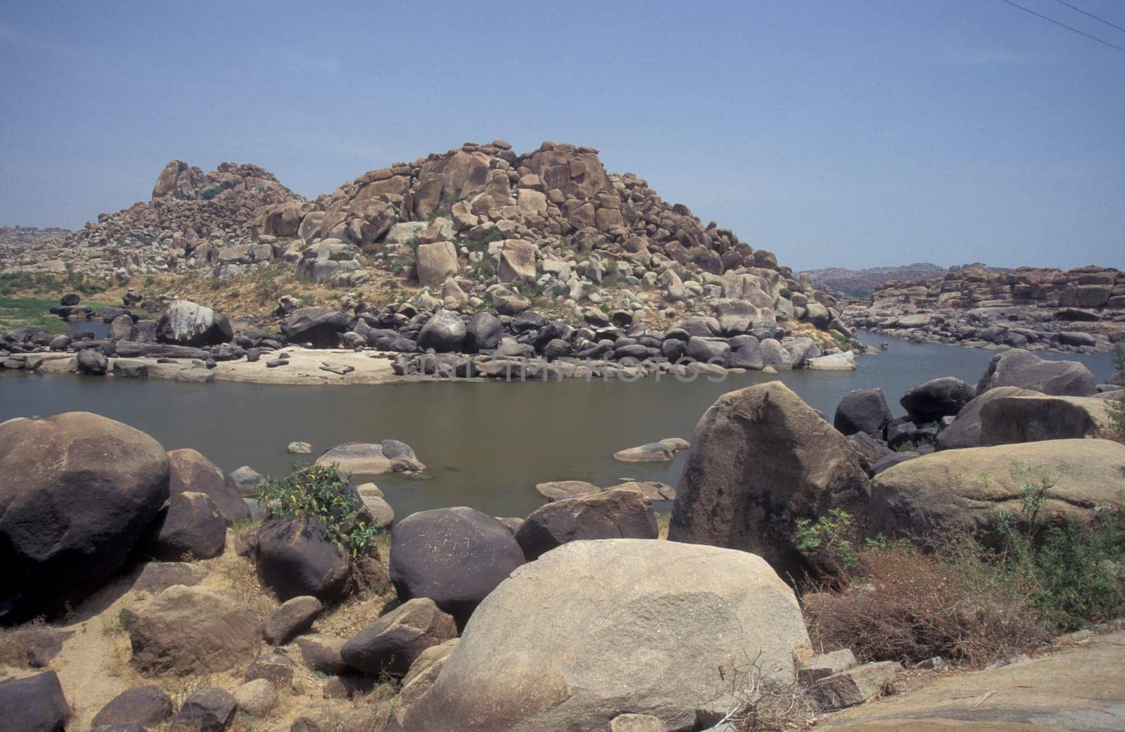 the Landscape and River with the typical Stones and Hills round of the town of Hampi in the Province of Karnataka in India.  India, Karnataka, March, 1998