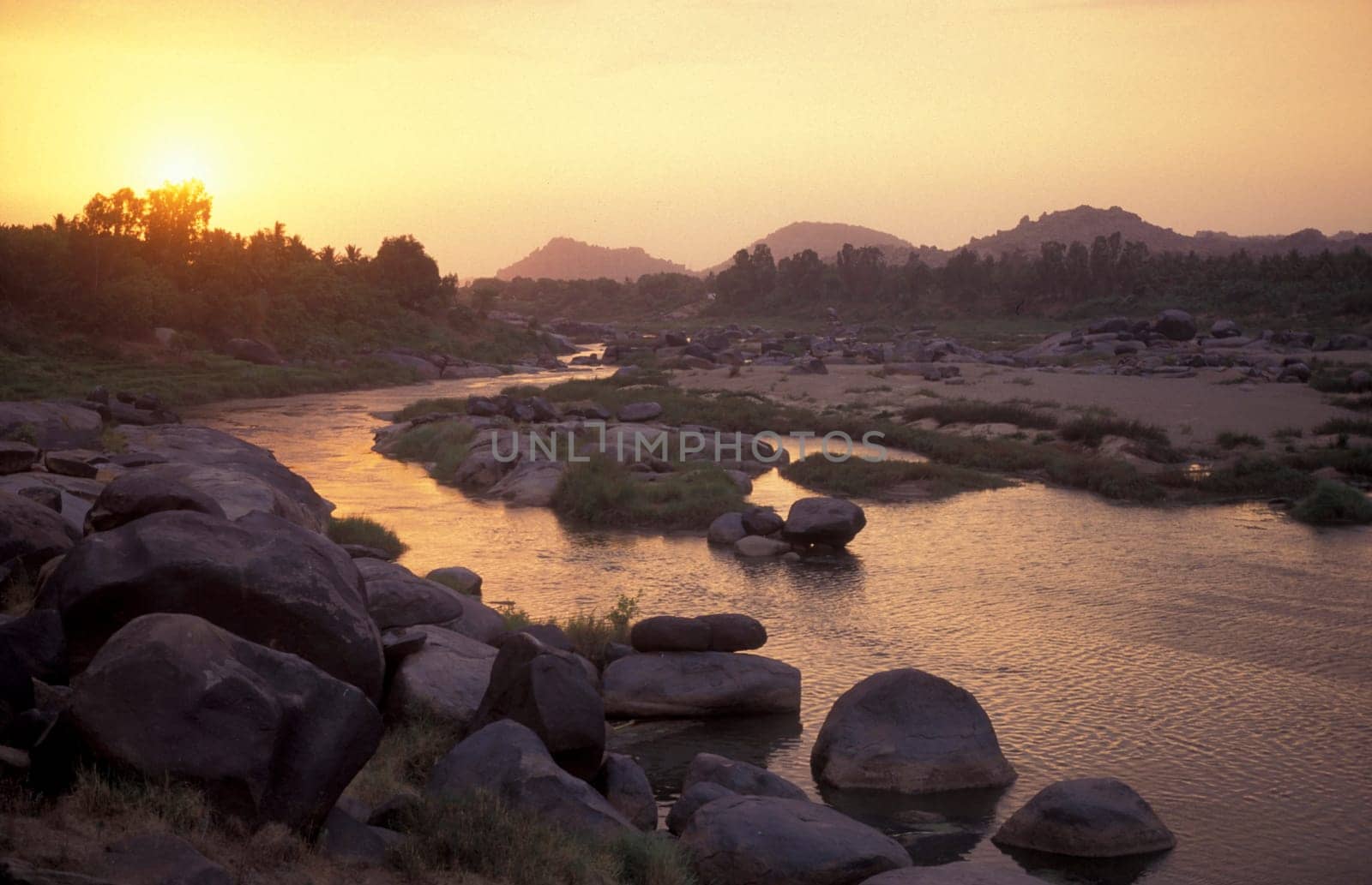 the Landscape and River with the typical Stones and Hills round of the town of Hampi in the Province of Karnataka in India.  India, Karnataka, March, 1998