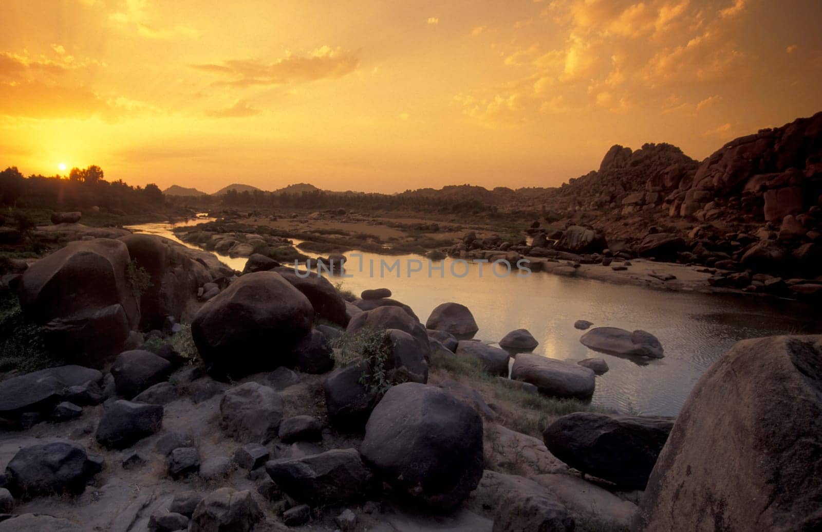 the Landscape and River with the typical Stones and Hills round of the town of Hampi in the Province of Karnataka in India.  India, Karnataka, March, 1998