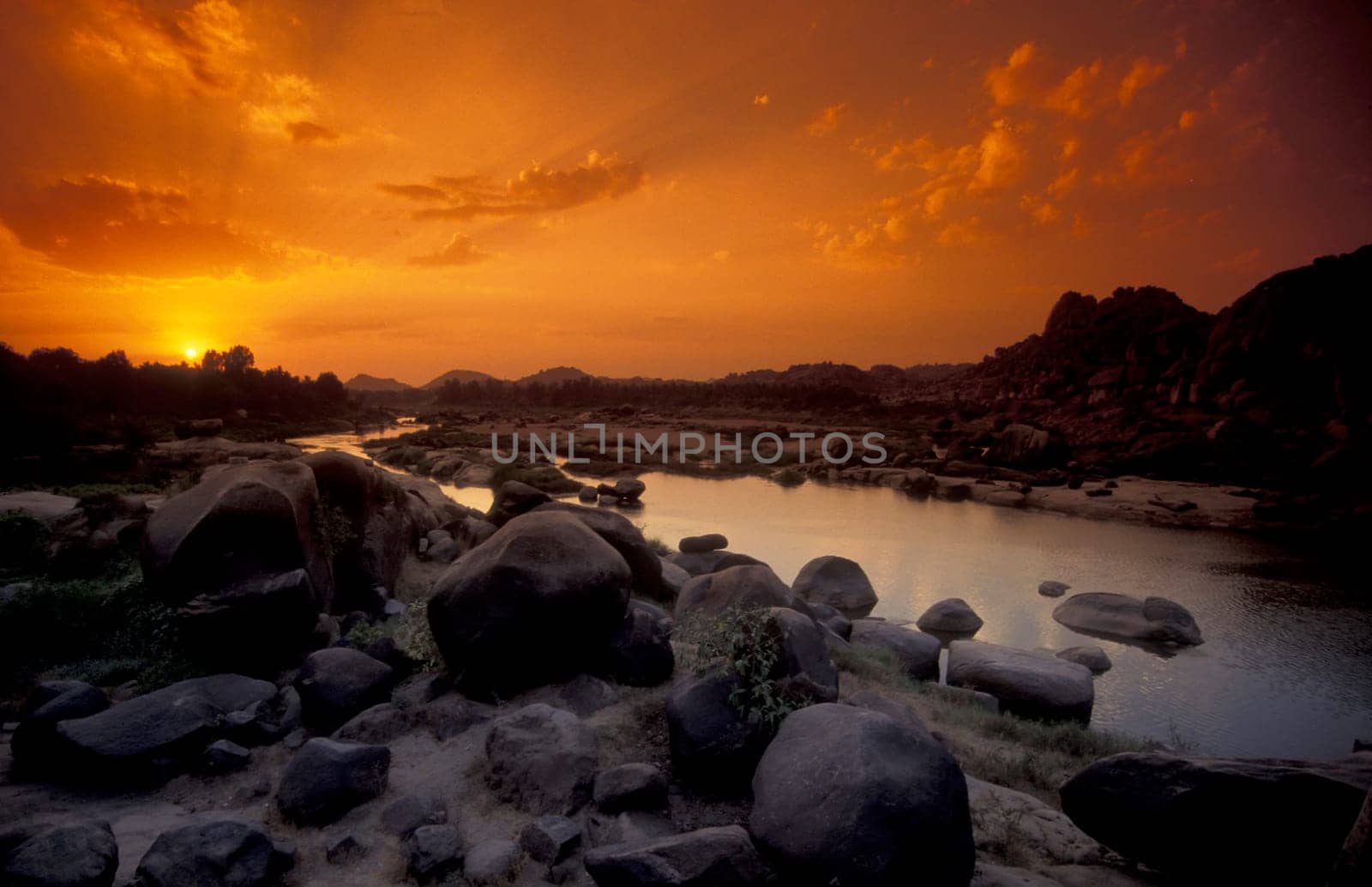 the Landscape and River with the typical Stones and Hills round of the town of Hampi in the Province of Karnataka in India.  India, Karnataka, March, 1998
