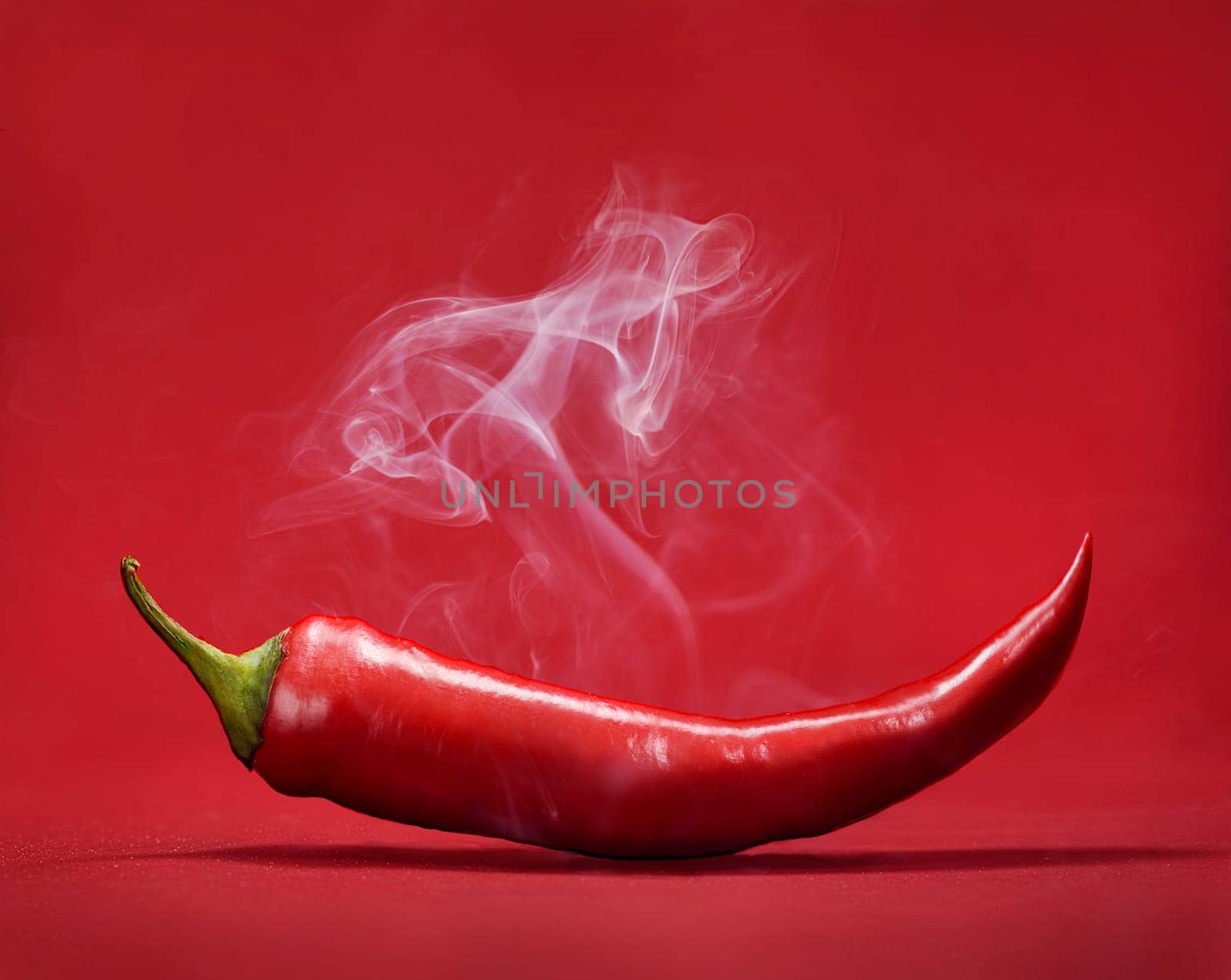 Red hot chili pepper on red background with smoke. Still life with steam mexican paprika spice.