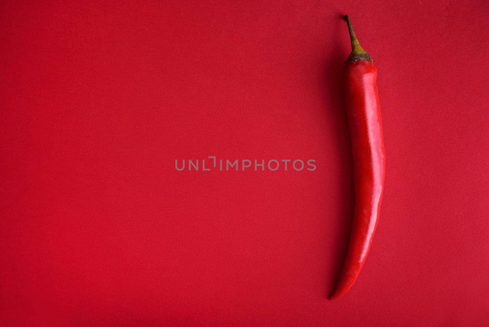 Food background flat lay. Red hot chili pepper on red background from above. Minimal creative still life with mexican spicy paprika.
