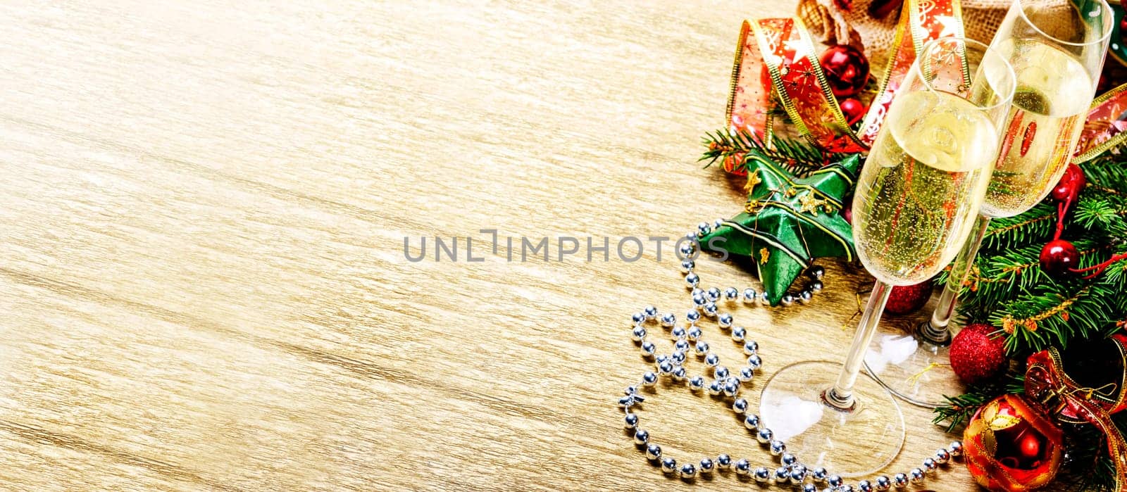 Luxury champagne glasses on gold backdrop. Christmas and new year decoration on golden textured background. Golden holiday banner layout with xmas ornamet and fir tree border. Top view.