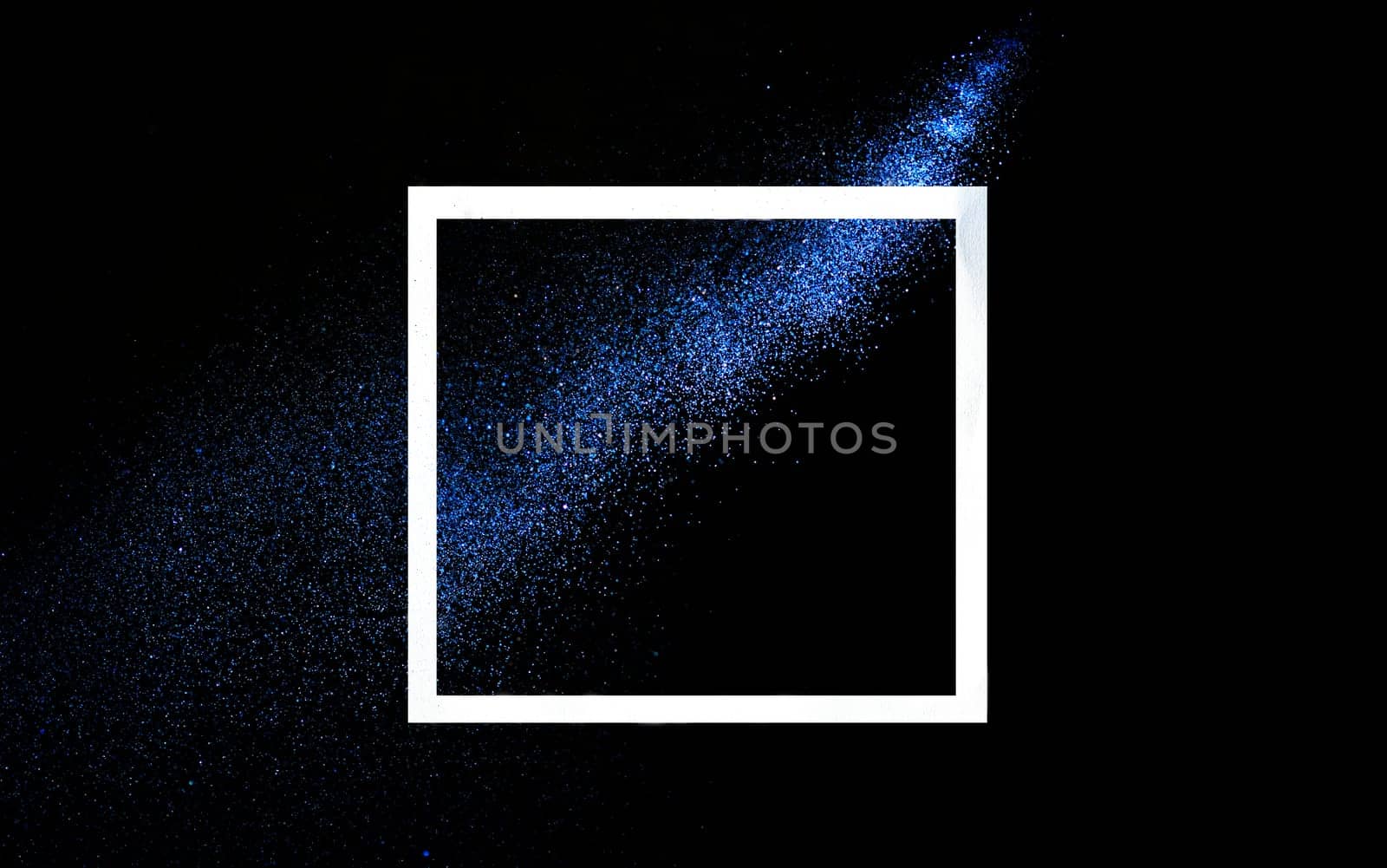 Creative frame concept with neon blue glitter splash trail on black background. Minimal flat lay design with star dust on dark backdrop. Holiday party modern style layout.