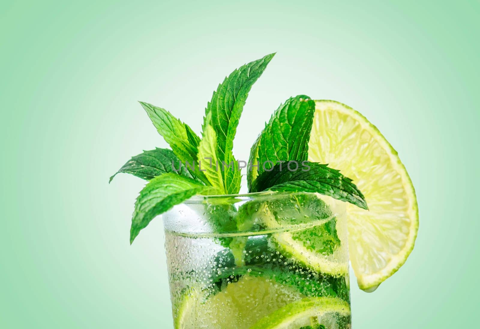 Closeup mojito cocktail with ice isolated over pastel background. Fresh mohito drink with lime and mint. Happy hour and beverage menu design.