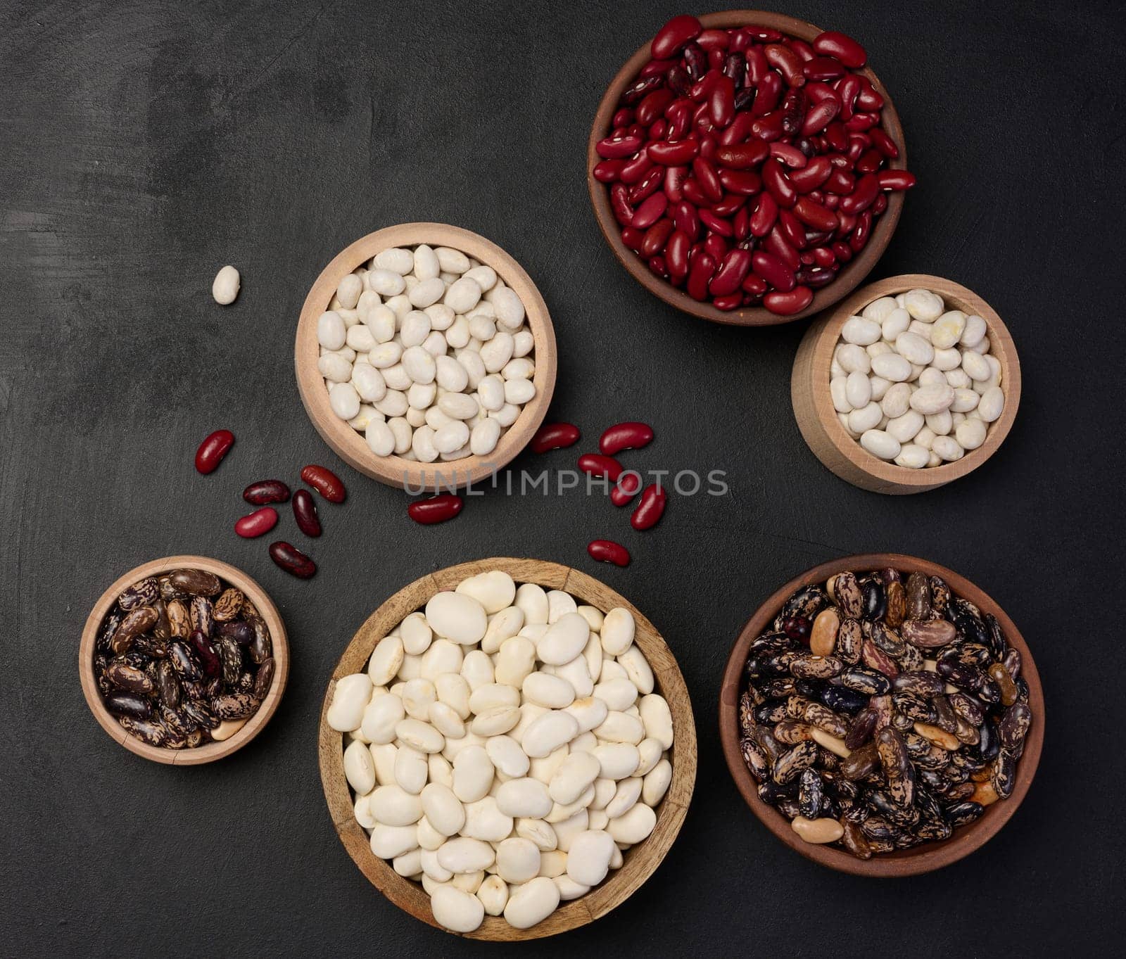 Raw white and red beans in a plate on a black table, top view. Assortment