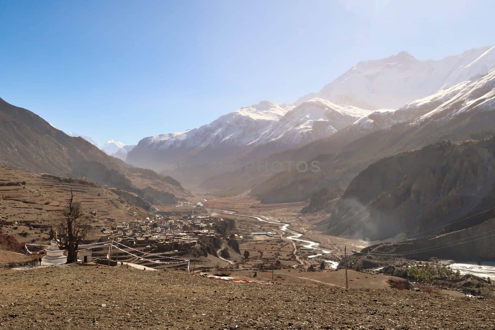 View from the trail back to the village of Gunsang, the town of Manang and the Marsyangdi River, the wind stirs up a lot of dust over the valley, Annapurna Circuit Trek, Nepal 2022