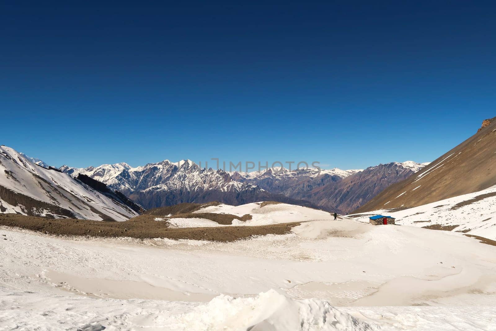 The trail down from Thorong La, Thorung La, Thorang La pass to Muktinath running through a snow covered landscape in front of a mountain range, Annapurna Circuit Trek, Nepal 2022