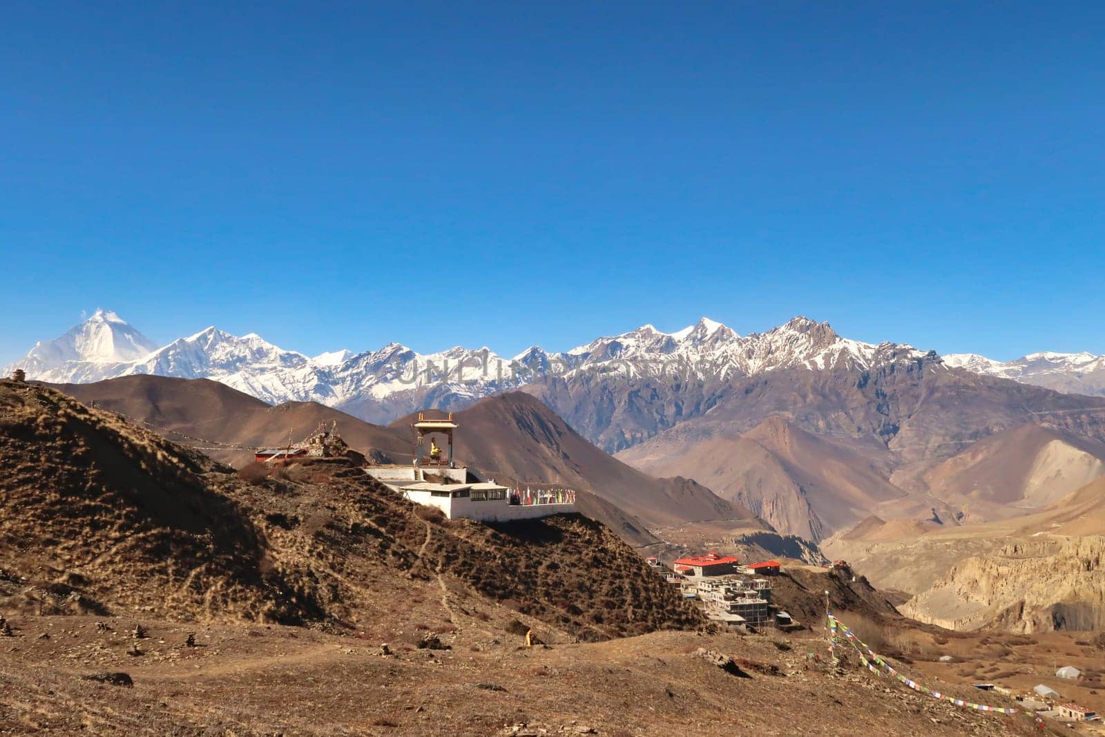 The Guru Rinpoche View Point in a hilly, dry landscape outside of the town of Muktinath in front of a snow capped mountain range with Dhaulagiri I on the left, Annapurna Circuit Trek, Nepal 2022