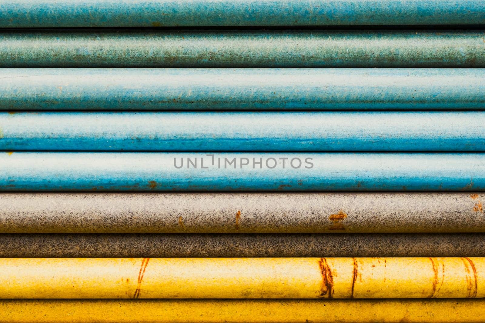 Stacked pipes, transitioning colors, blue, brown and yellow, abstract closeup shot