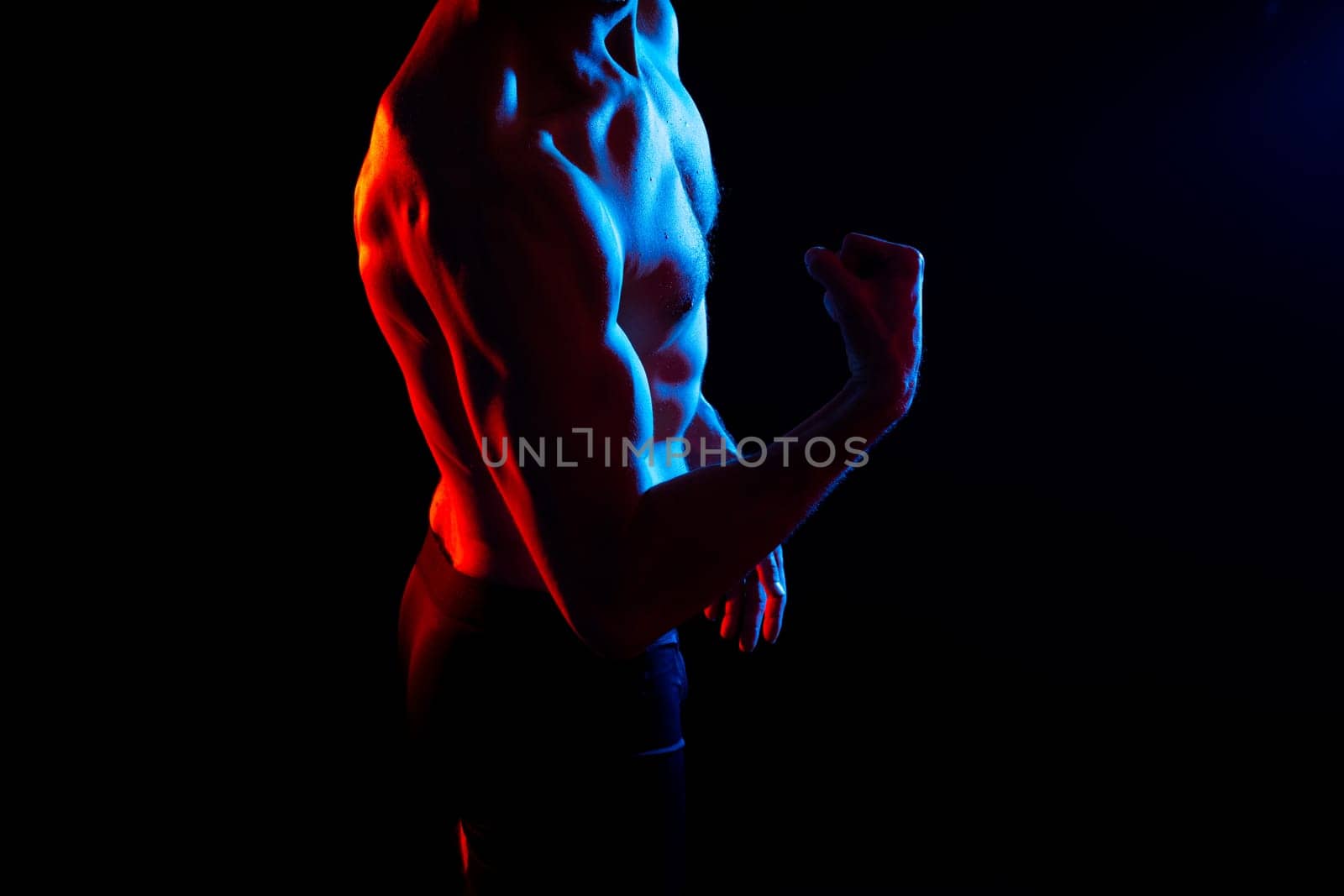 Image of muscle man posing in a studio, dark white red background