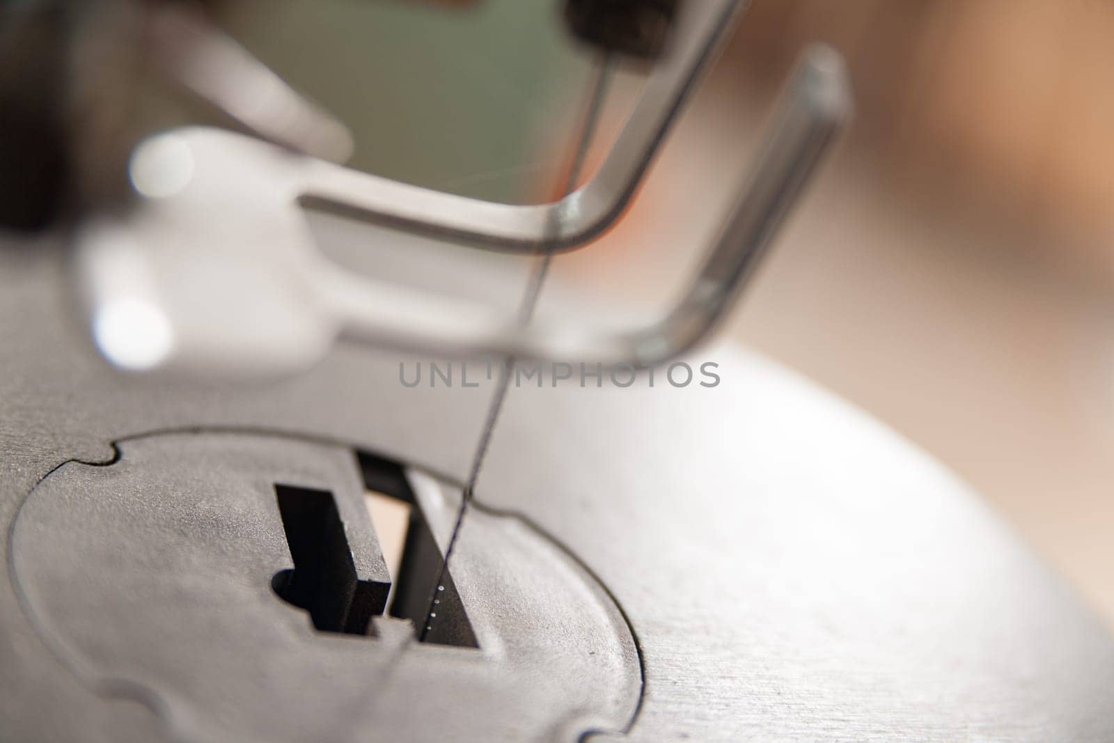 Scroll saw blade cutting through a piece of wood in a carpentry workshop, shallow depth of field with focus on the blade