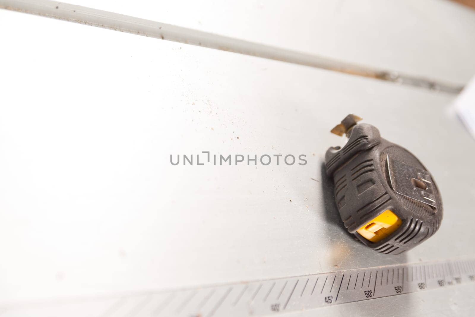 Busy workshop with a measuring tape on a metal table, sawdust scattered around, showcasing carpentry tools and precision in construction work