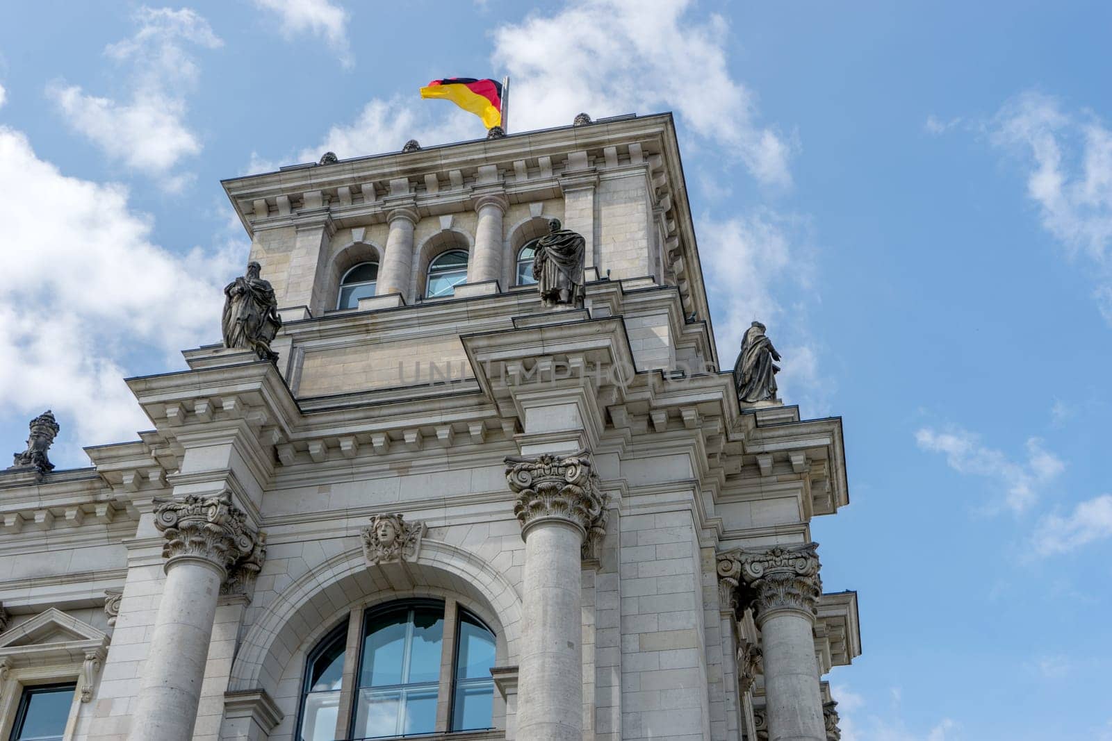 Detailed shot of the Berlin Reichstag against a blue sky with white clouds