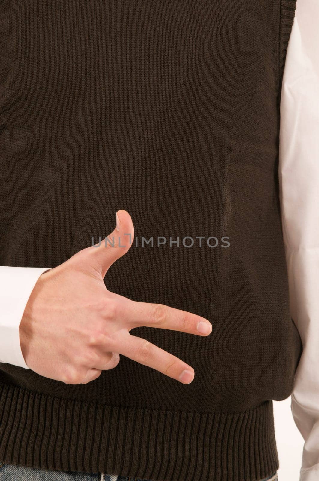 A male hand held in front of the stomach symbolizes the number 3 with the fingers.