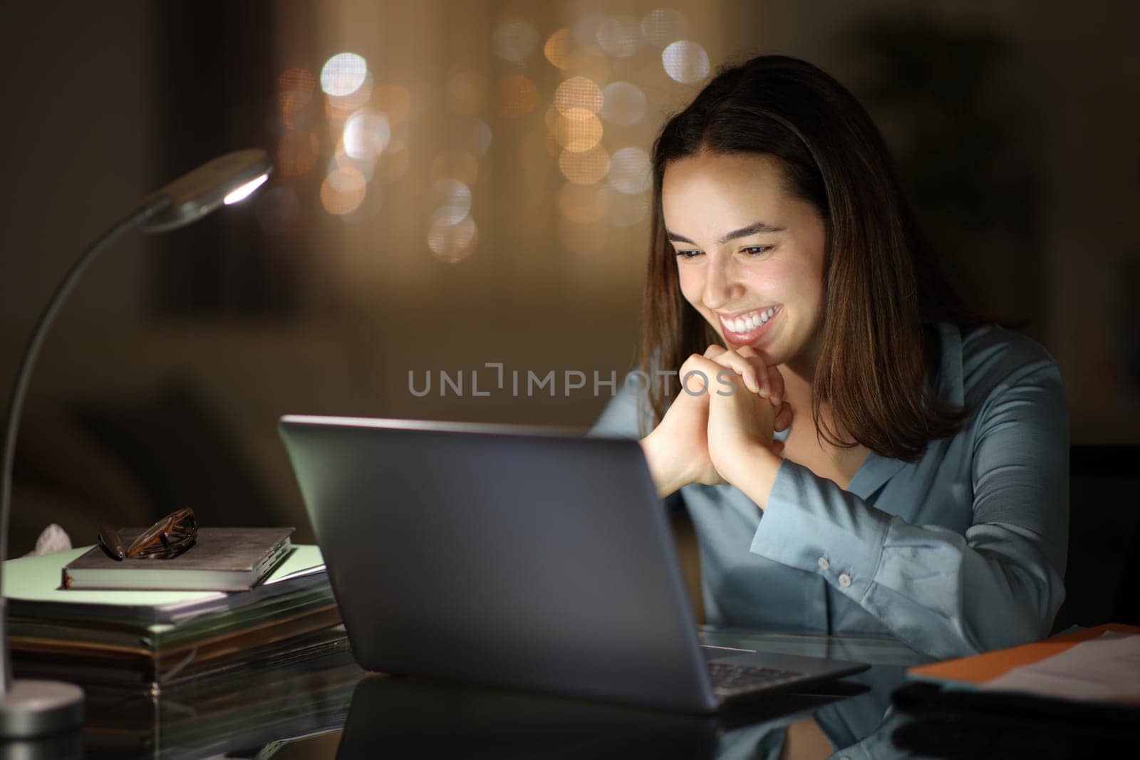 Happy businesswoman is checking laptop in the night at home