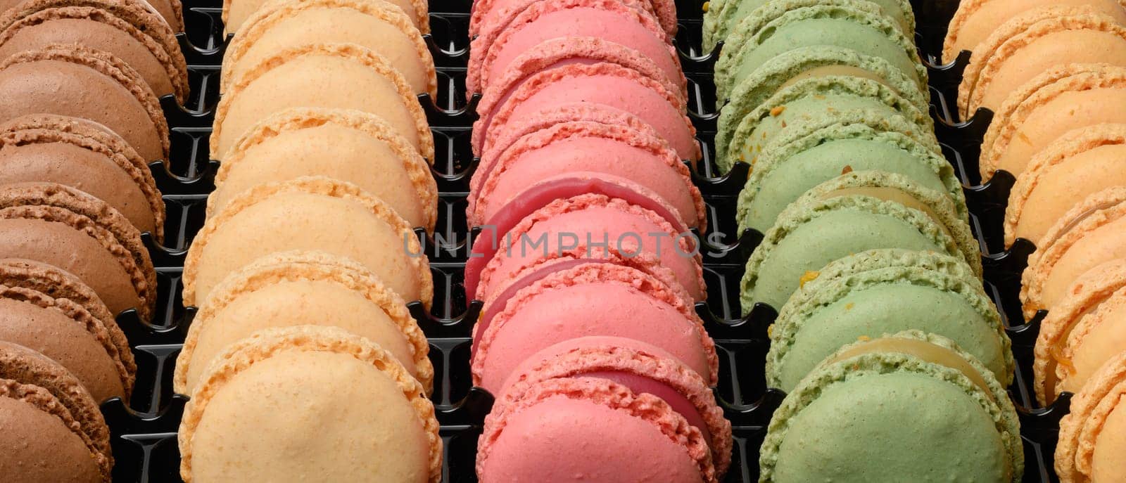 Multi-colored macarons in a plastic box, top view. Assortment