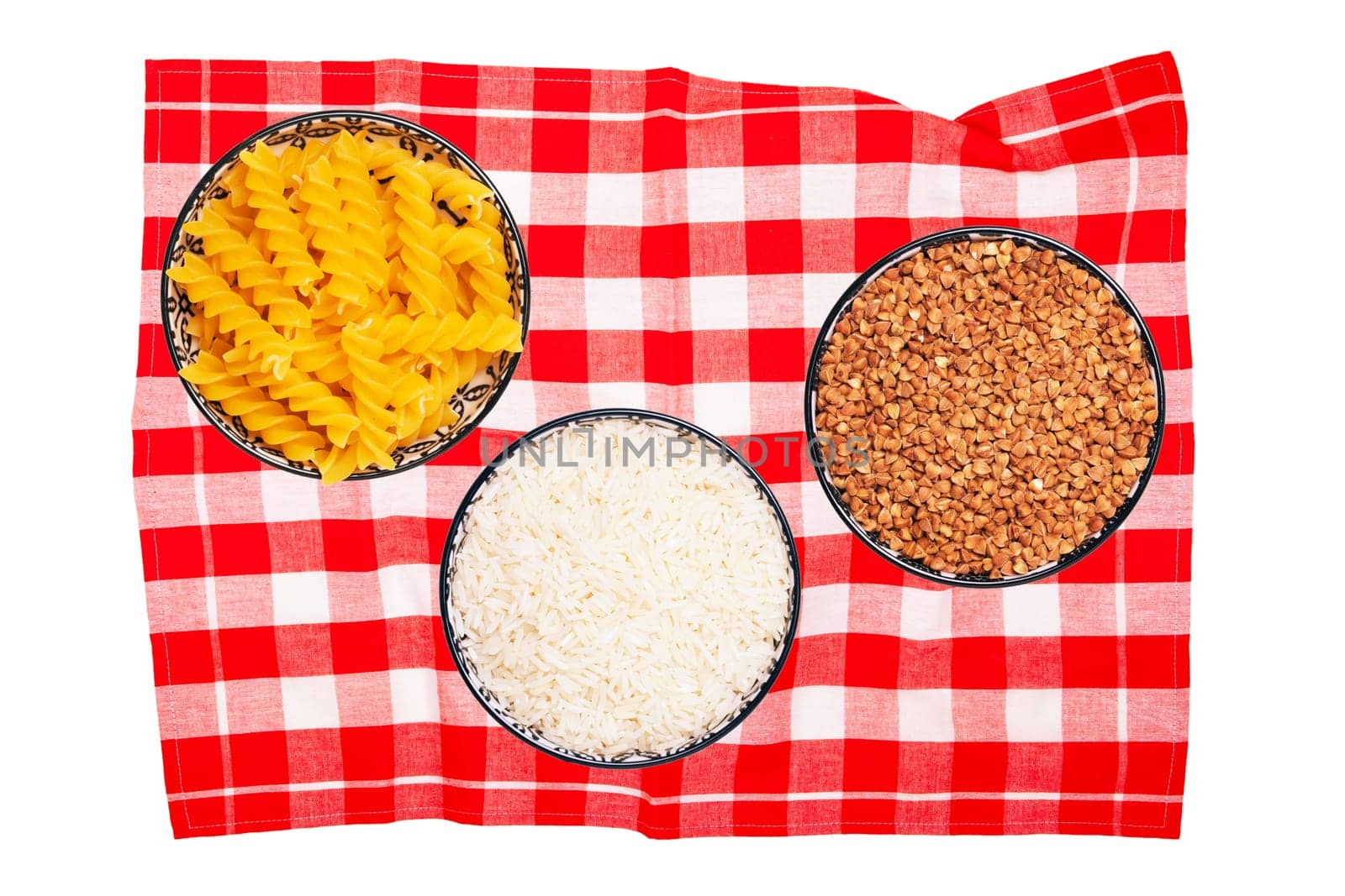 Vegetable food. Close-up of three bowls with buckwheat, noodles, rice on a red checkered tablecloth isolated. Healthy eating and nutrition. Top view with space for product montage.