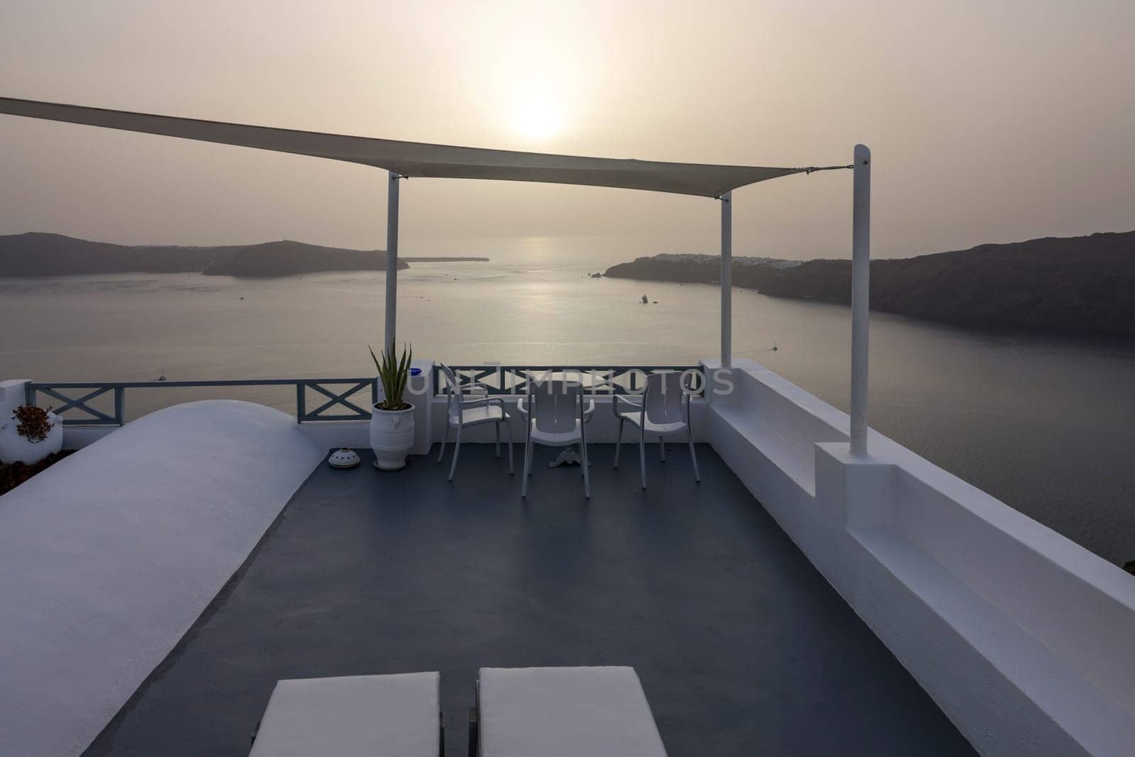 Chairs on terrace in the village of Imerovigli with amazing view of sunset over caldera in Santorini, Greece