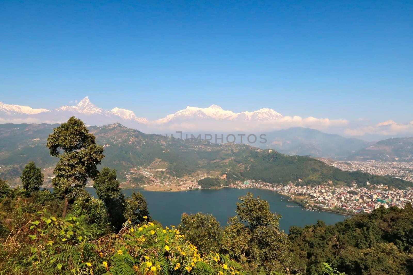 View onto Phewa Lake, the town of Pokhara and the mountain range rising behind it, with Mount Machapuchare on the left, on the way up to the World Peace Pagoda, Pokhara, Nepal 2022