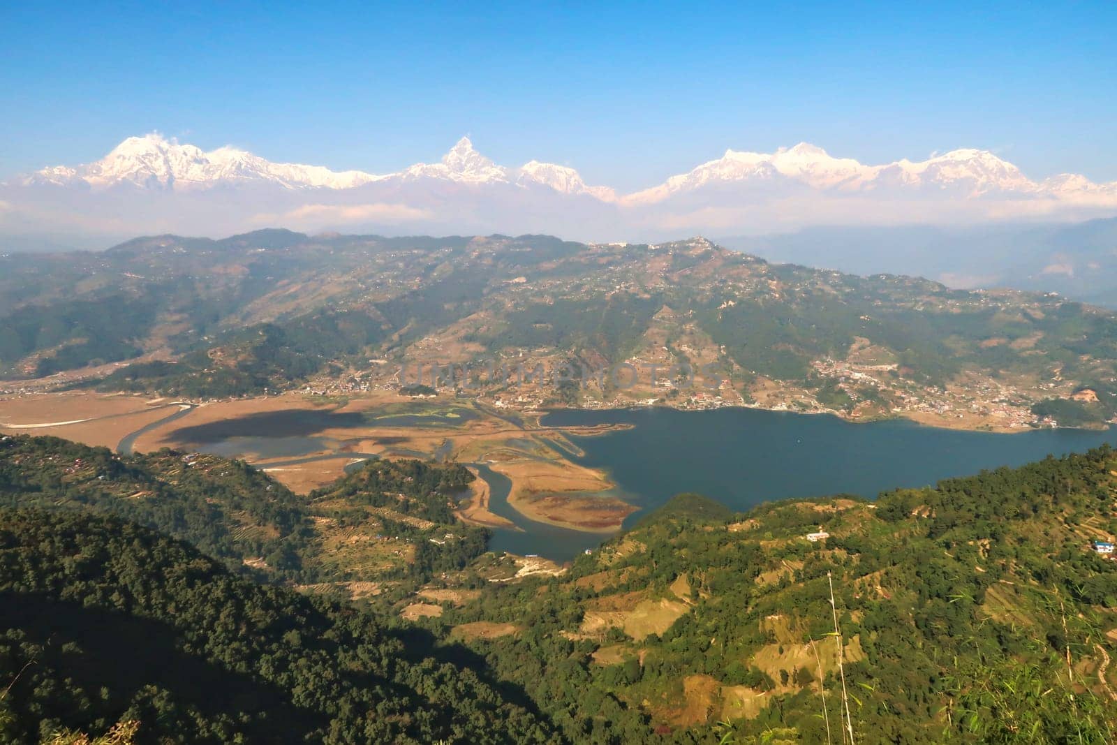 View onto Phewa Lake in front of a mountain range with Mount Machapuchare in the middle, on the way up to the World Peace Pagoda close to Pokhara, Nepal 2022