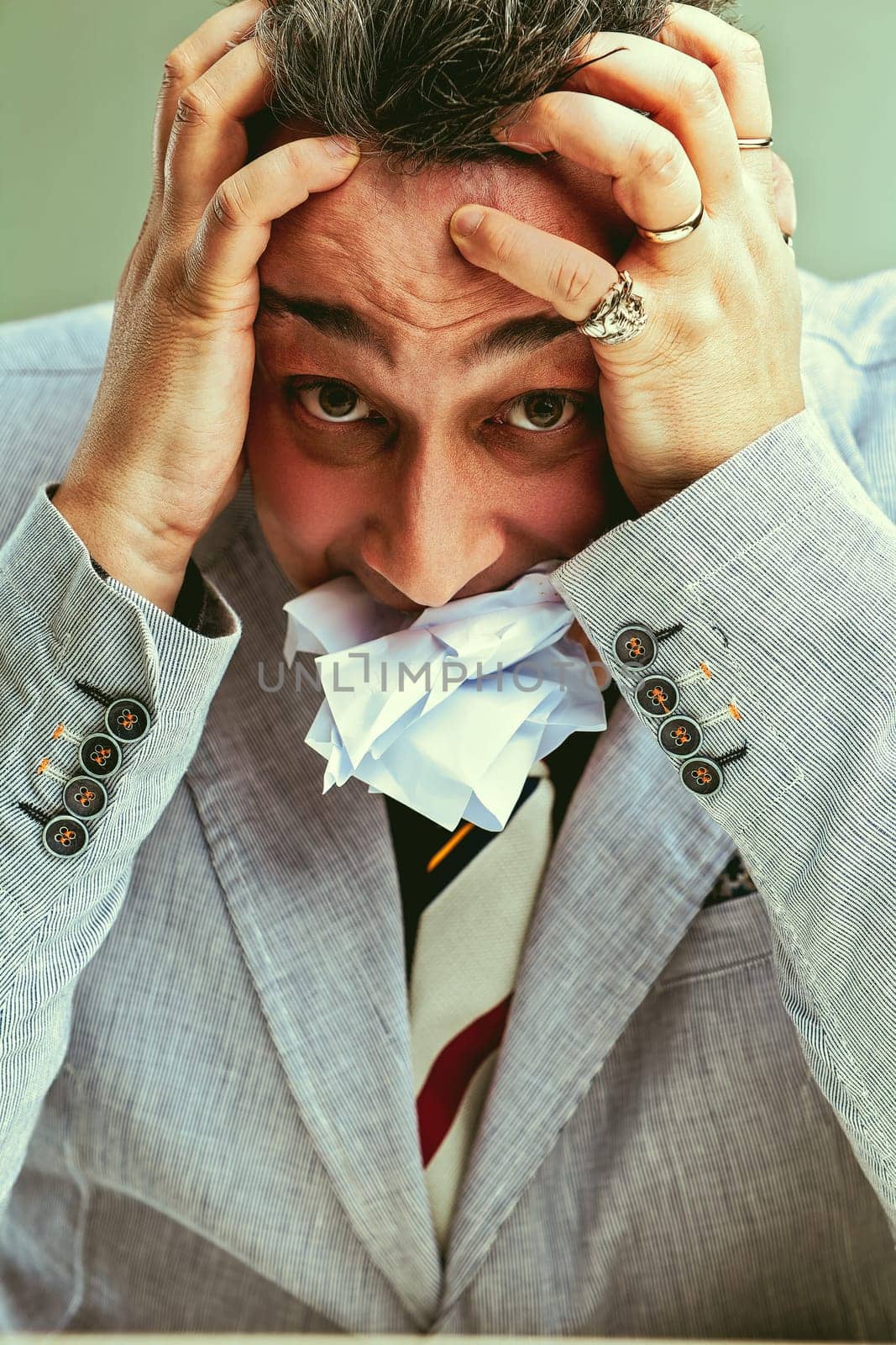 Stressed businessman stuffing mouth with paper to cope with pressure and responsibility