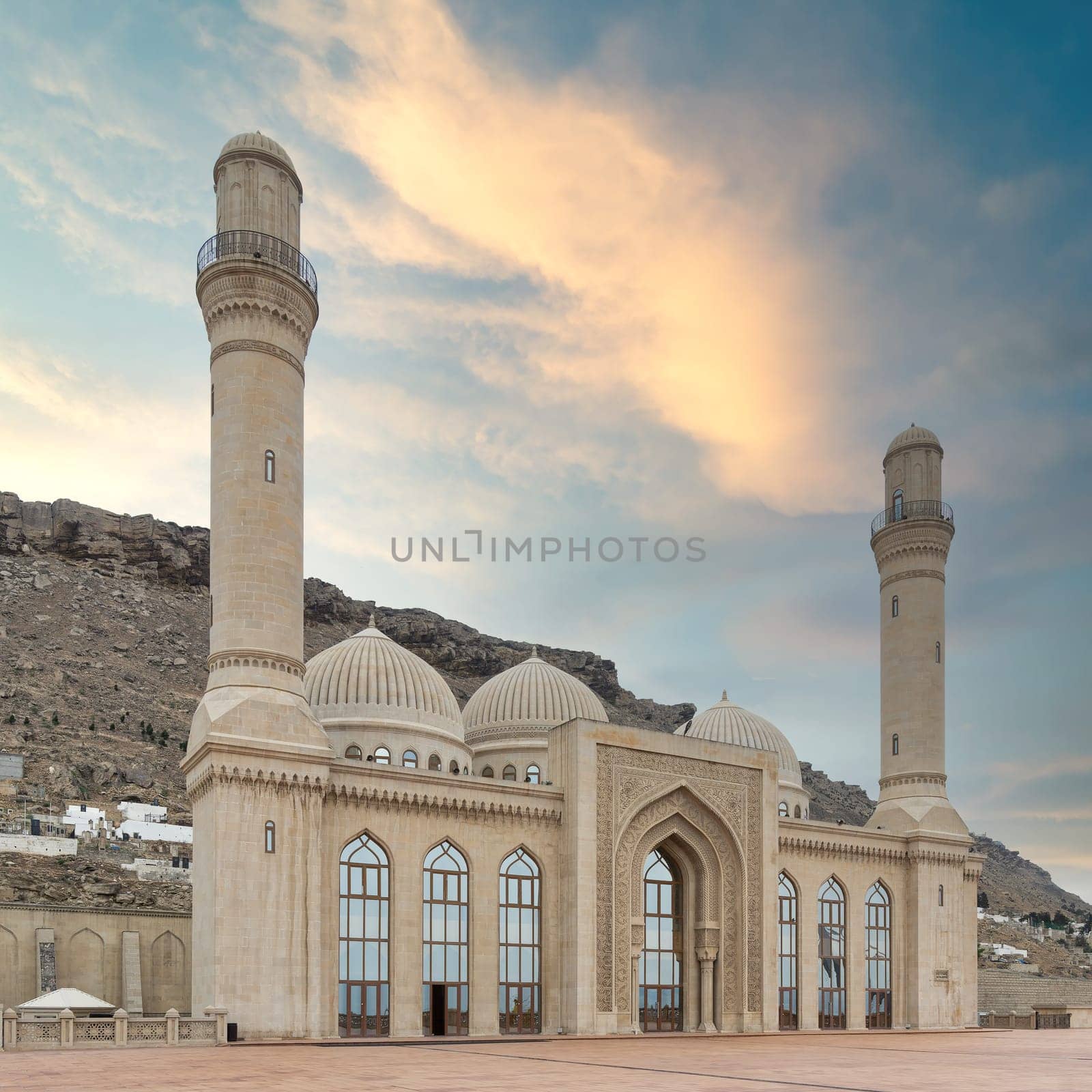 The Bibi-Heybat Mosque in Baku, Azerbaijan showcases stunning Islamic architecture with minarets, domes, and intricate details. Set against hills, it stands out against sunset