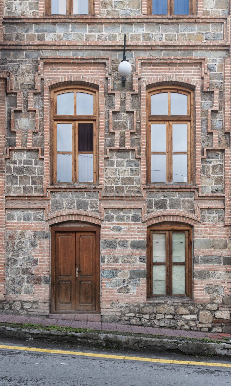 A well-preserved building features unique stonework and ornate windows, showcasing architectural beauty in a charming urban setting