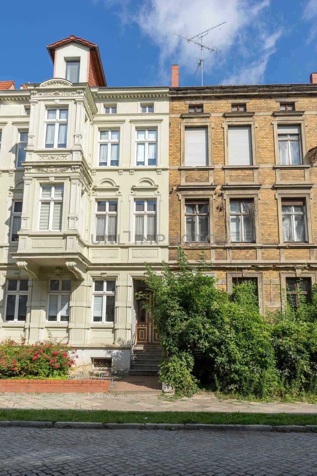 A renovated and a dilapidated terraced house with several floors and a front garden