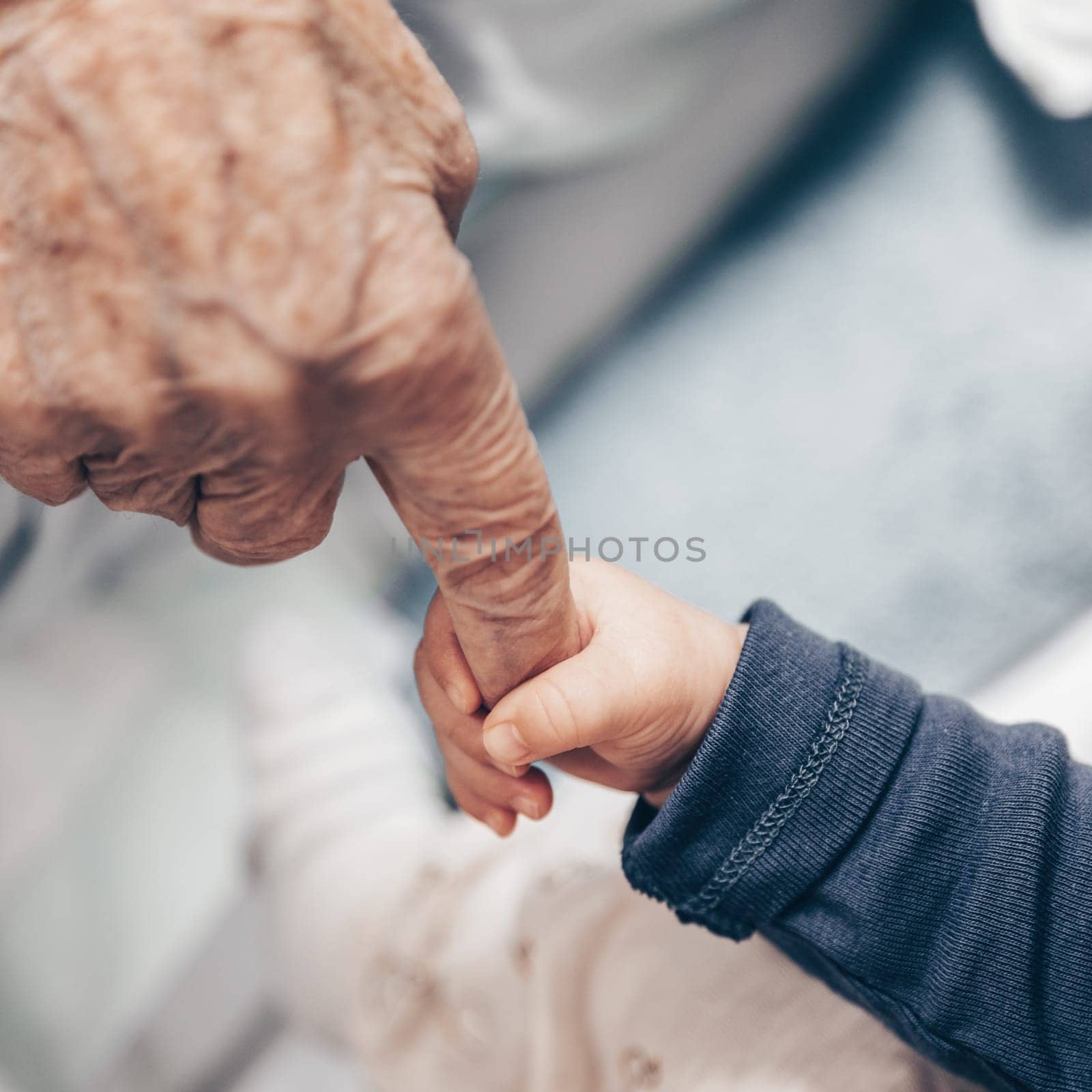 Circle of life. Little baby boy child hand holding great grandmother wrinkled finger. Intergenerational help and solidarity concept.