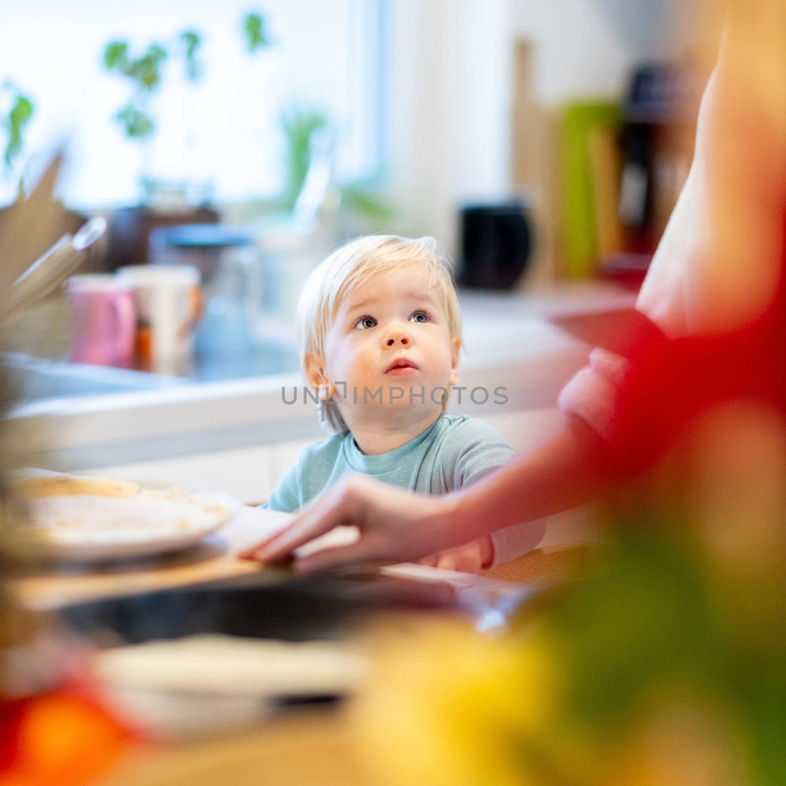 Mother and little toddler baby boy making pancakes for breakfast together in domestic kitchen. Family, lifestyle, domestic life, food, healthy eating and people concept