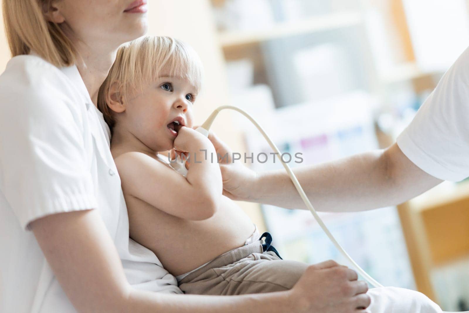 Small child being checked for heart murmur by heart ultrasound exam by cardiologist as part of regular medical checkout at pediatrician