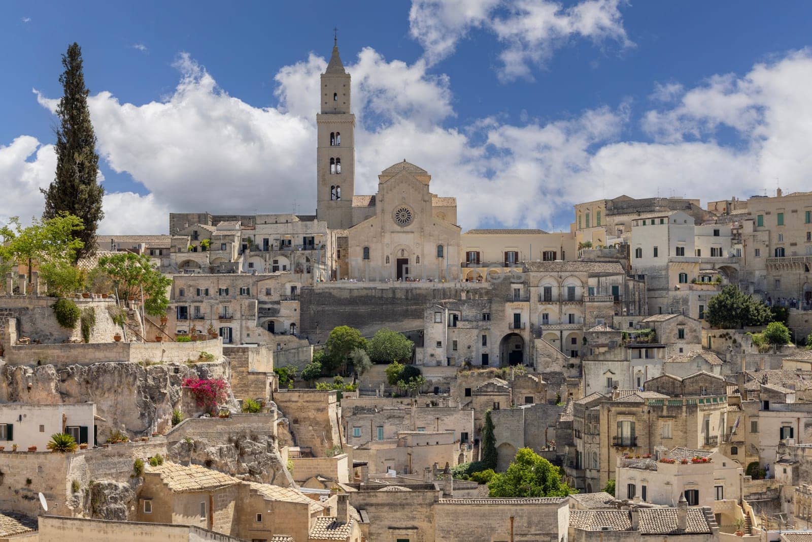 Italy, Matera - May 22, 2024: Panoramic view from Luigi Guerricchio Belvedere of historic city carved in rock Sassi of Matera. Bell tower of Matera Cathedral in a distance