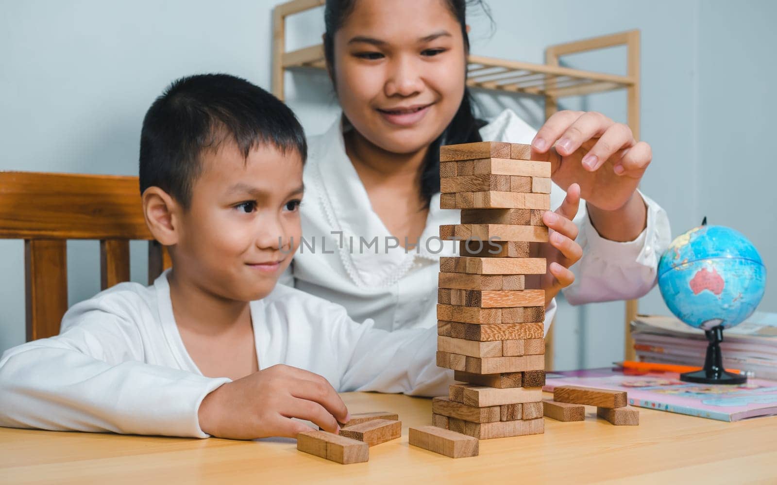Asian family spending time together on holiday on study desk at home, Mother play wood block toy with son in house, Activity relationship, Brain and concentration training games.