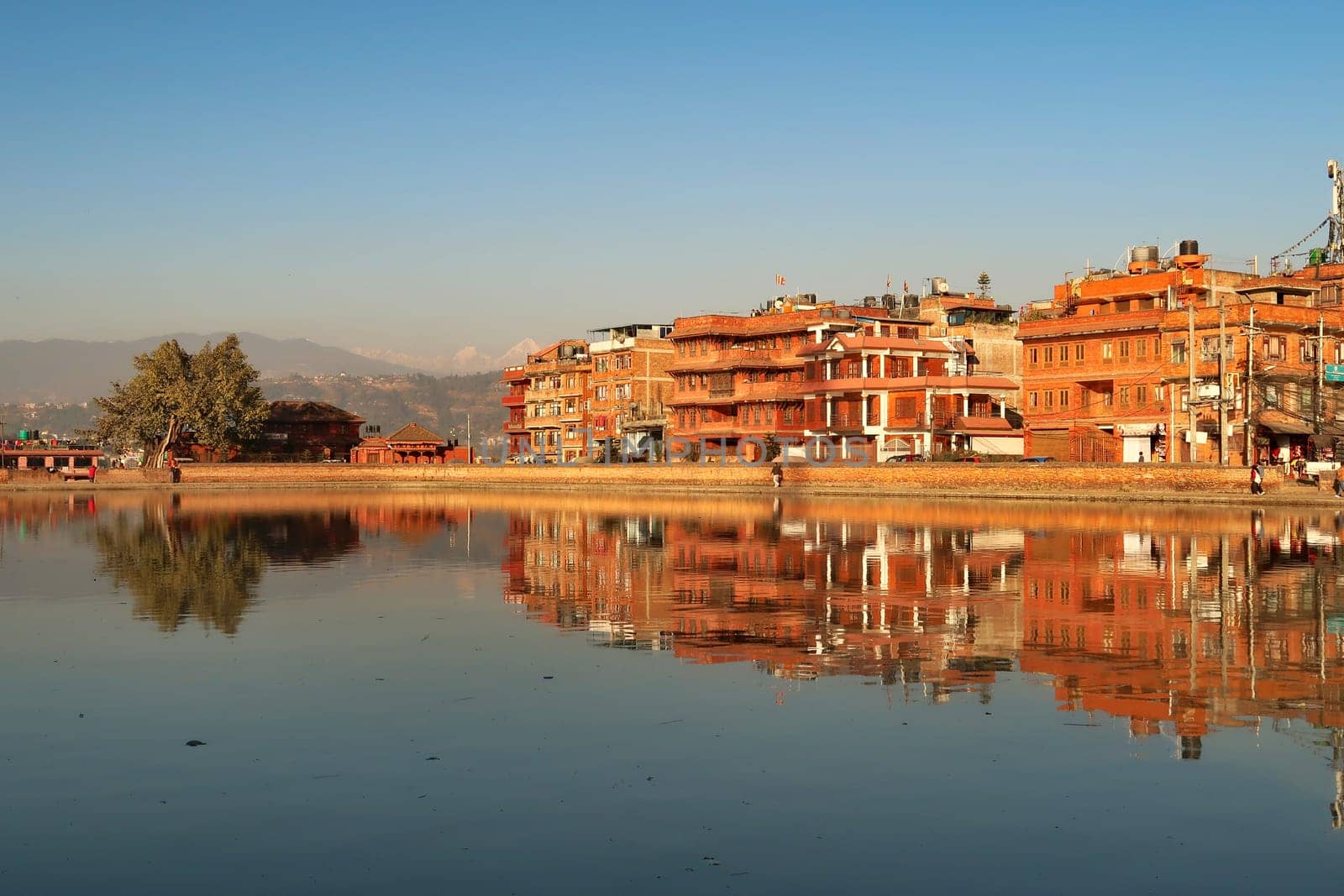 Golden hour at the Na Pukhu Lake, Pond in Bhaktapur, apartment, residential houses, buildings, dwellings are reflecting perfectly in the smooth surface of the water Bhaktapur, Nepal 2022