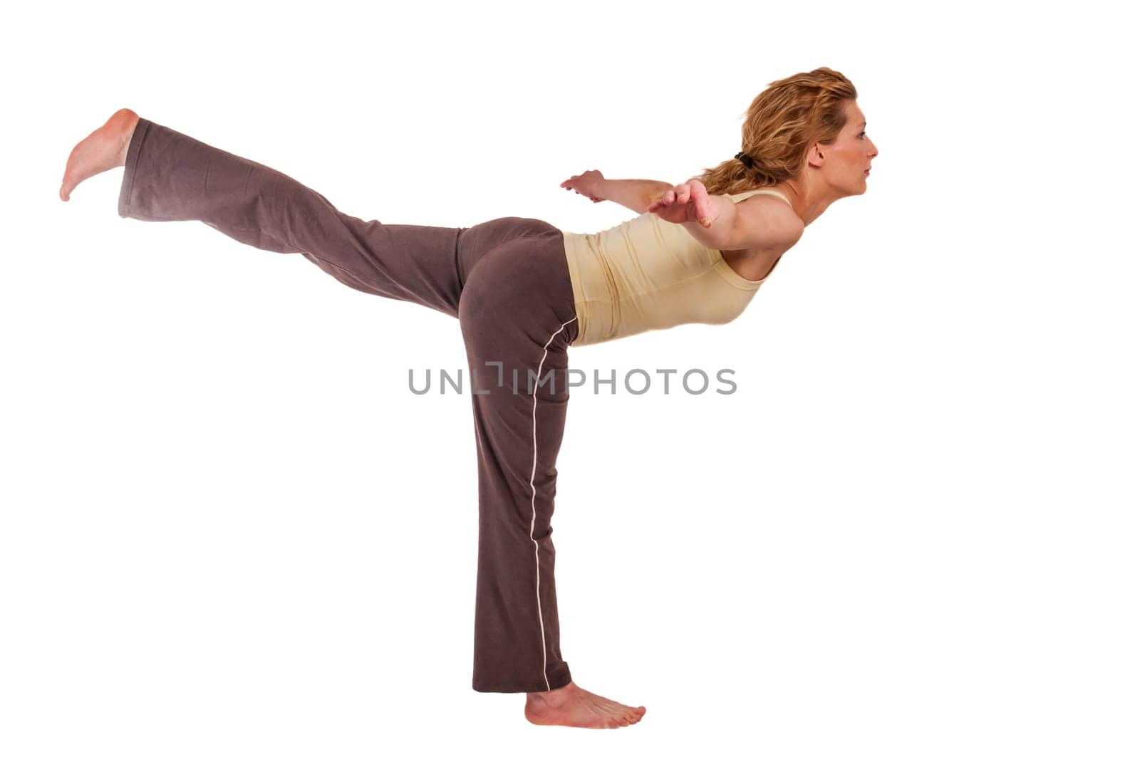 Side full body view of a young blonde woman in sportswear doing gymnastics exercise standing balance with arms outstretched isolated on white.