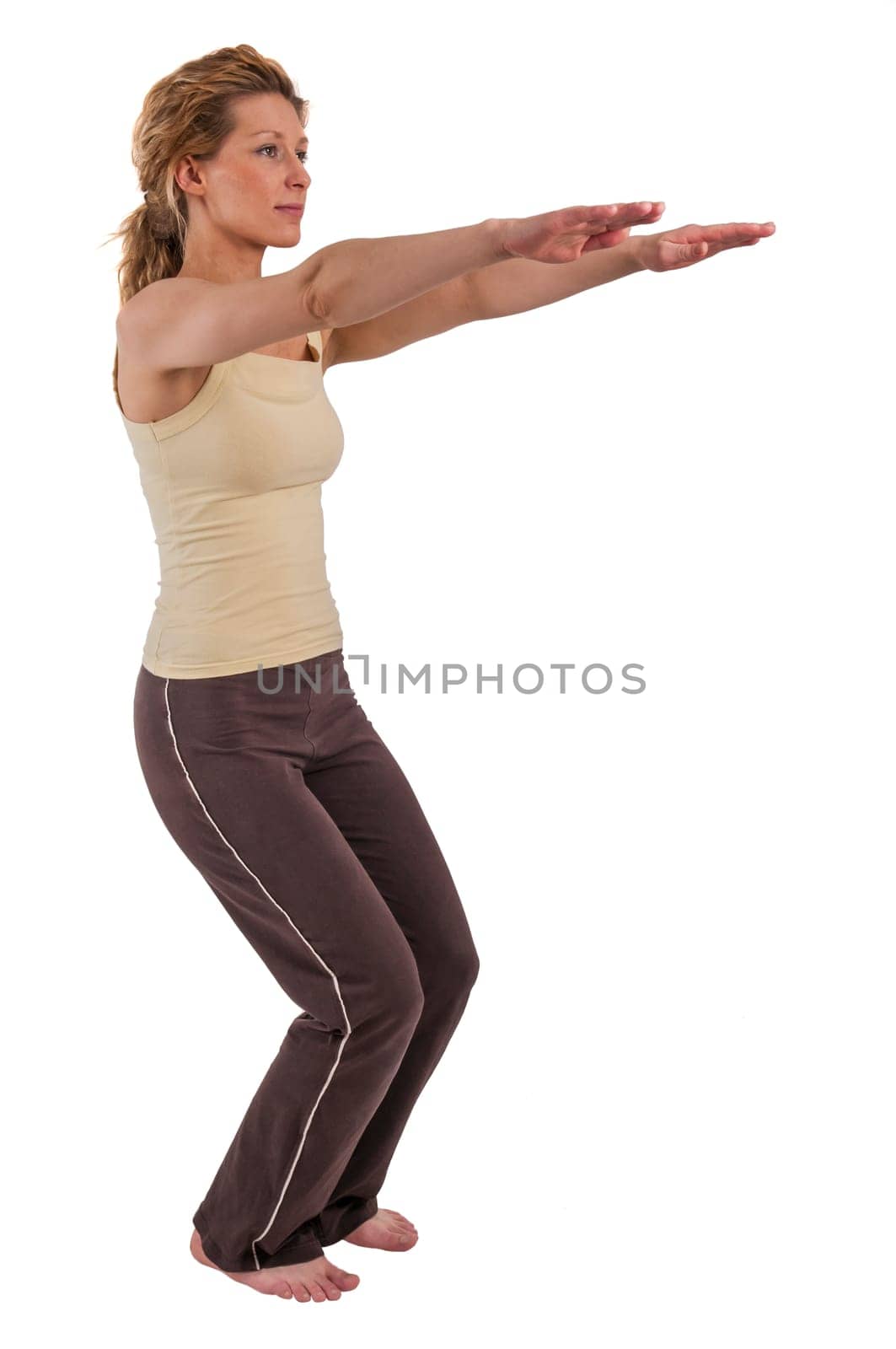 Three-quarter length full body view of a young blonde woman in sport dress showing sport exercise squat with outstretched arms isolated on white.