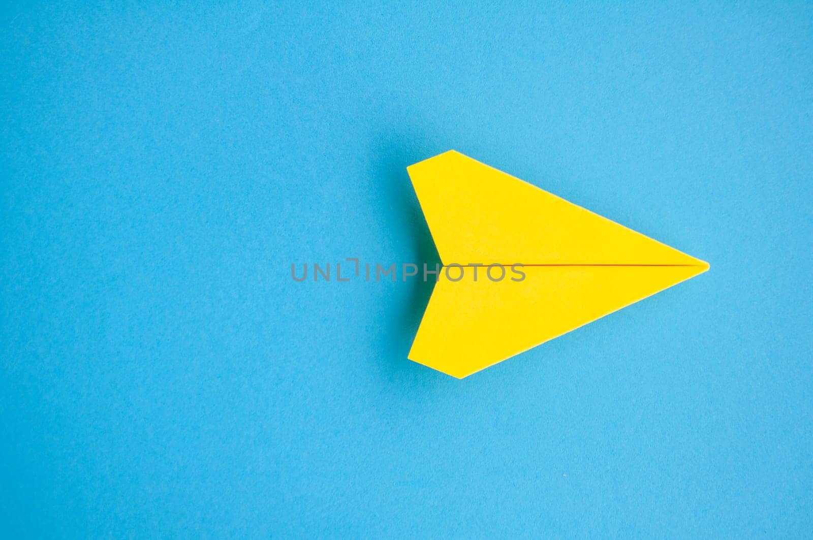 Top view of yellow paper airplane with customizable space for text or ideas.