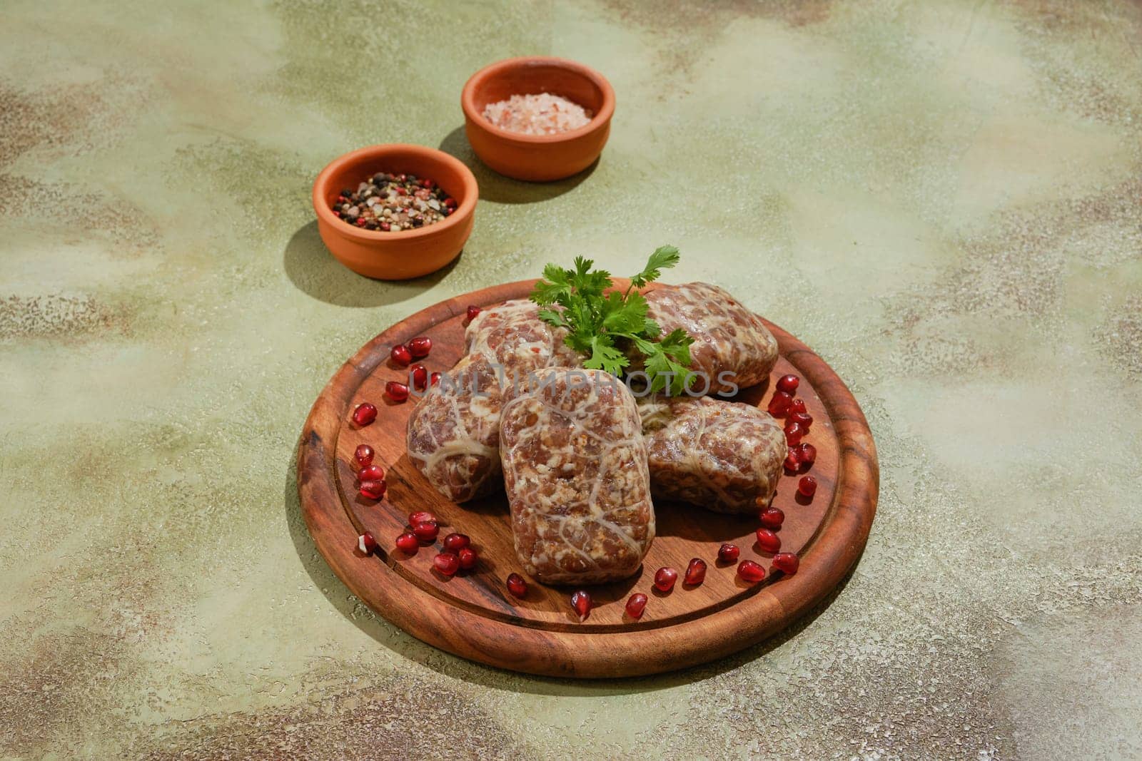 Georgian raw beef cutlets - Apkhazura, wrapped in fat net decorated with pomegranate seeds and cilantro