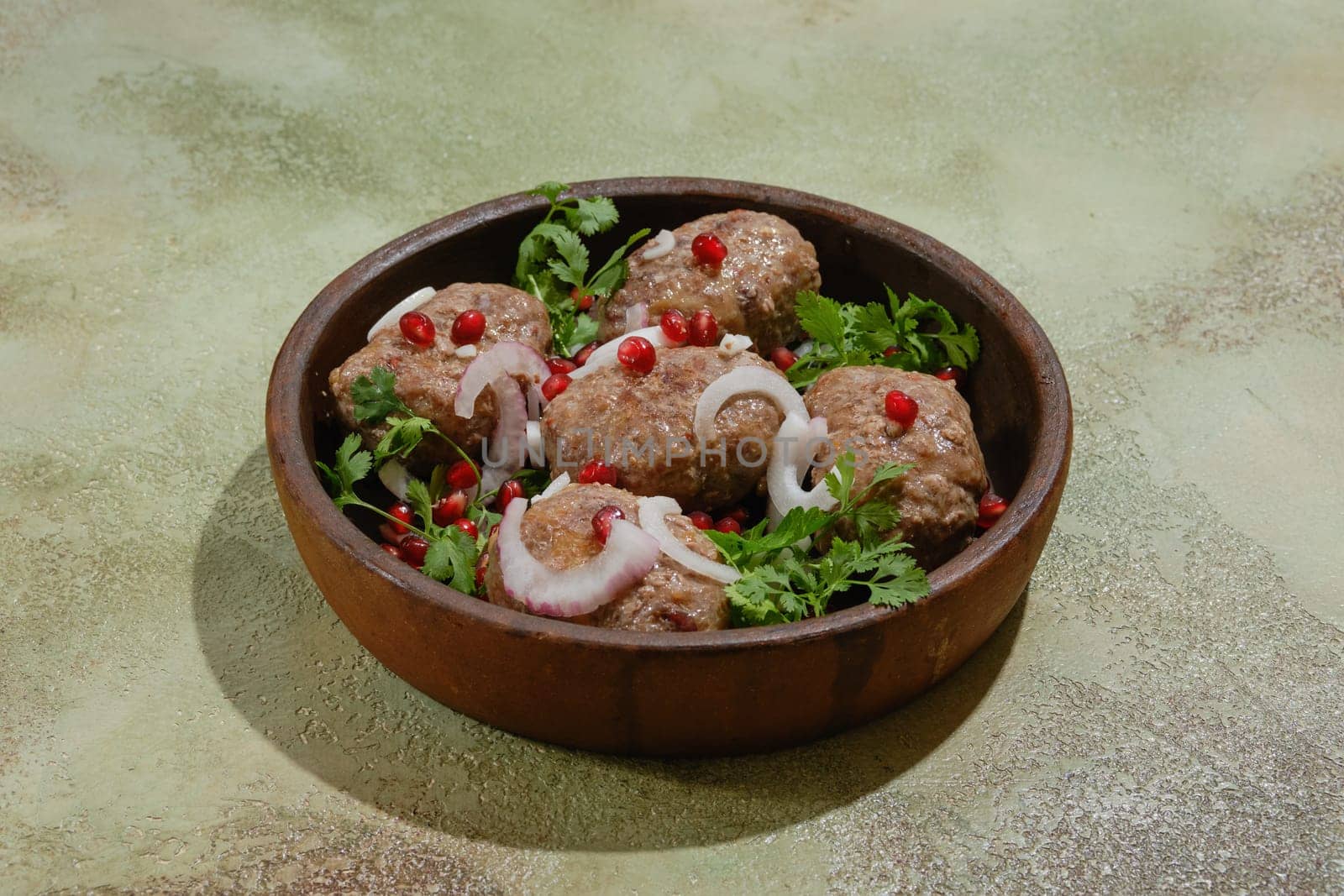 Georgian fried beef patties - Apkhazura in clay pot decorated with pomegranate seeds, slices of red onion and cilantro